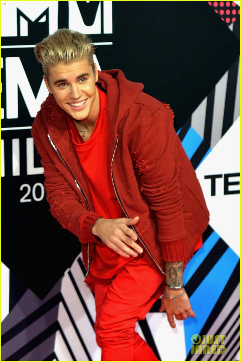 Justin Bieber 身穿紅色服裝在活動中對著鏡頭微笑