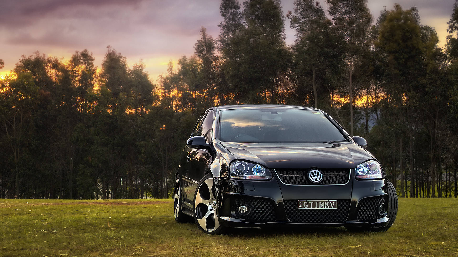 2015款黑色Volkswagen Golf GTI MKV 壁紙 — 一輛時尚的黑色福士 GTI 停泊在黃昏的草地上，背後樹木閃耀著光芒。