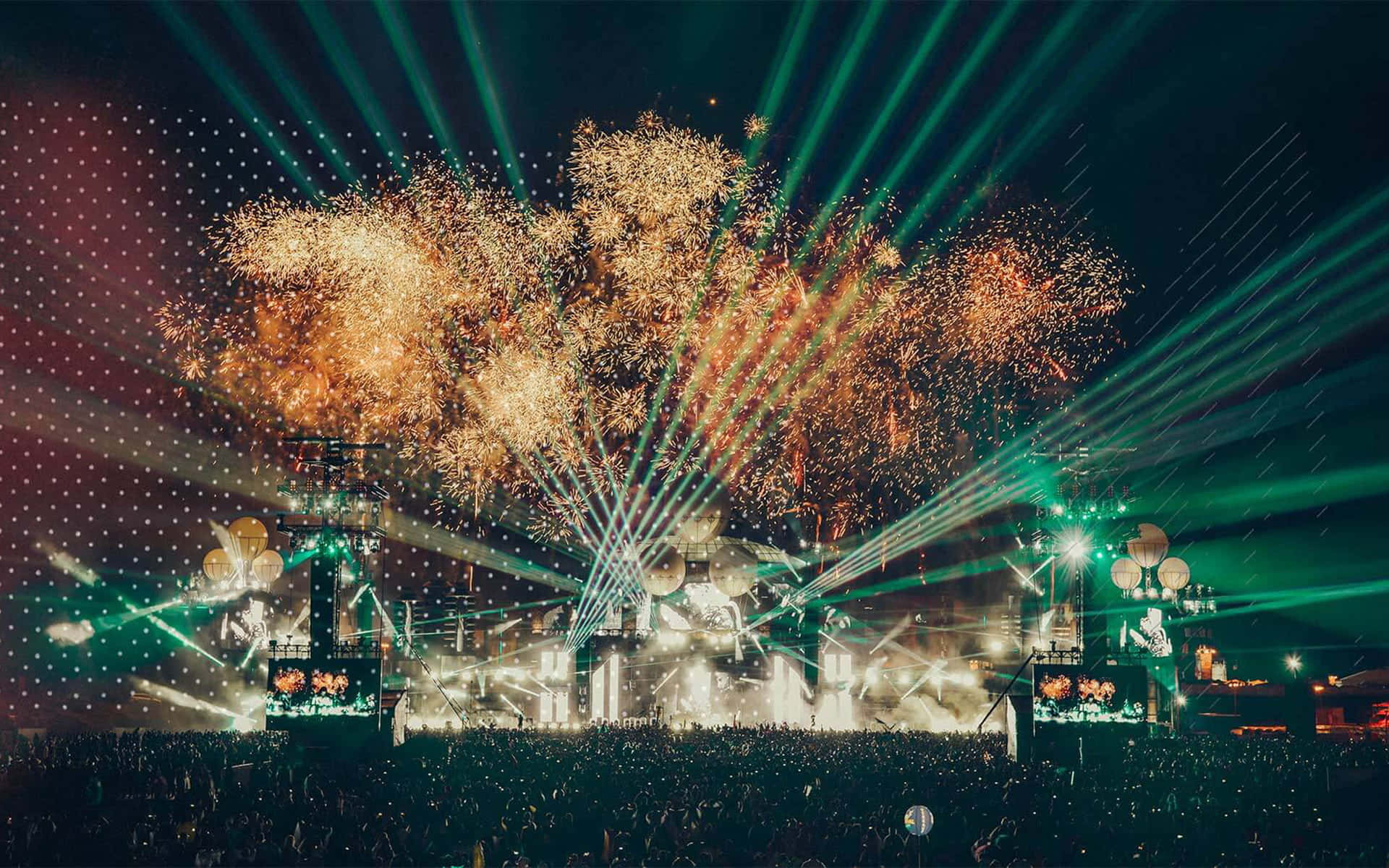 2017 德國Parookaville音樂節演唱會舞台背景 壁紙 — 大量演唱會觀眾觀看壯觀的煙火在夜間被綠色激光束籠罩的舞台上空爆炸。