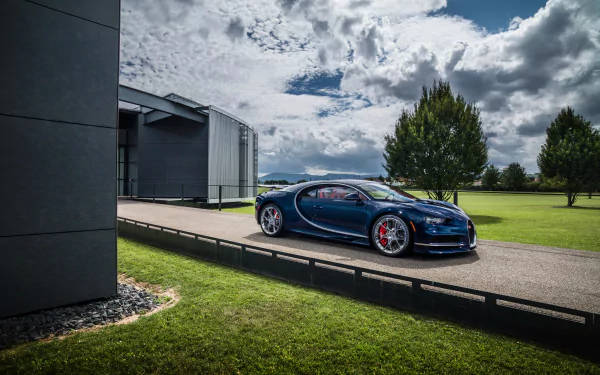 藍色Bugatti跑車停泊在現代建築和綠色草坪附近，天空多雲。