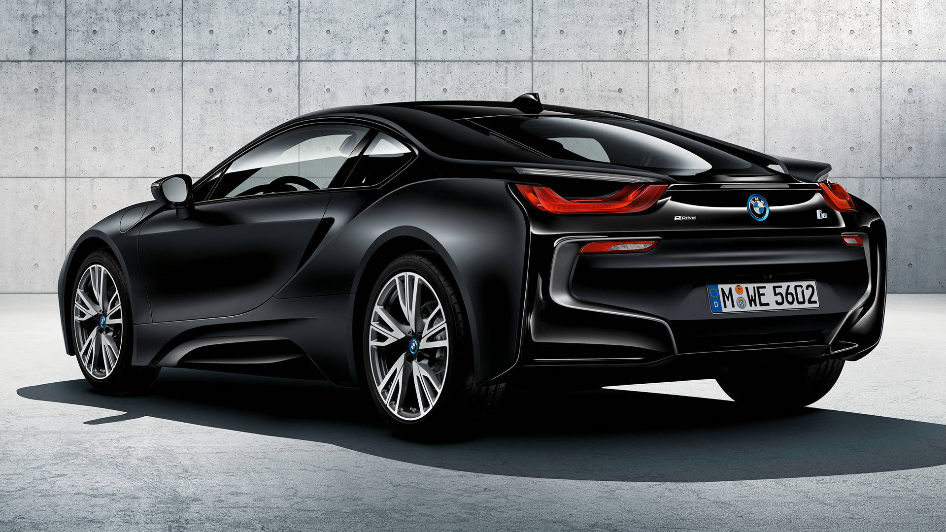 2017黑色BMW i8後視圖 壁紙 — 一輛時尚的黑色BMW i8跑車，帶紅色尾燈，停放在有紋理的混凝土牆旁。