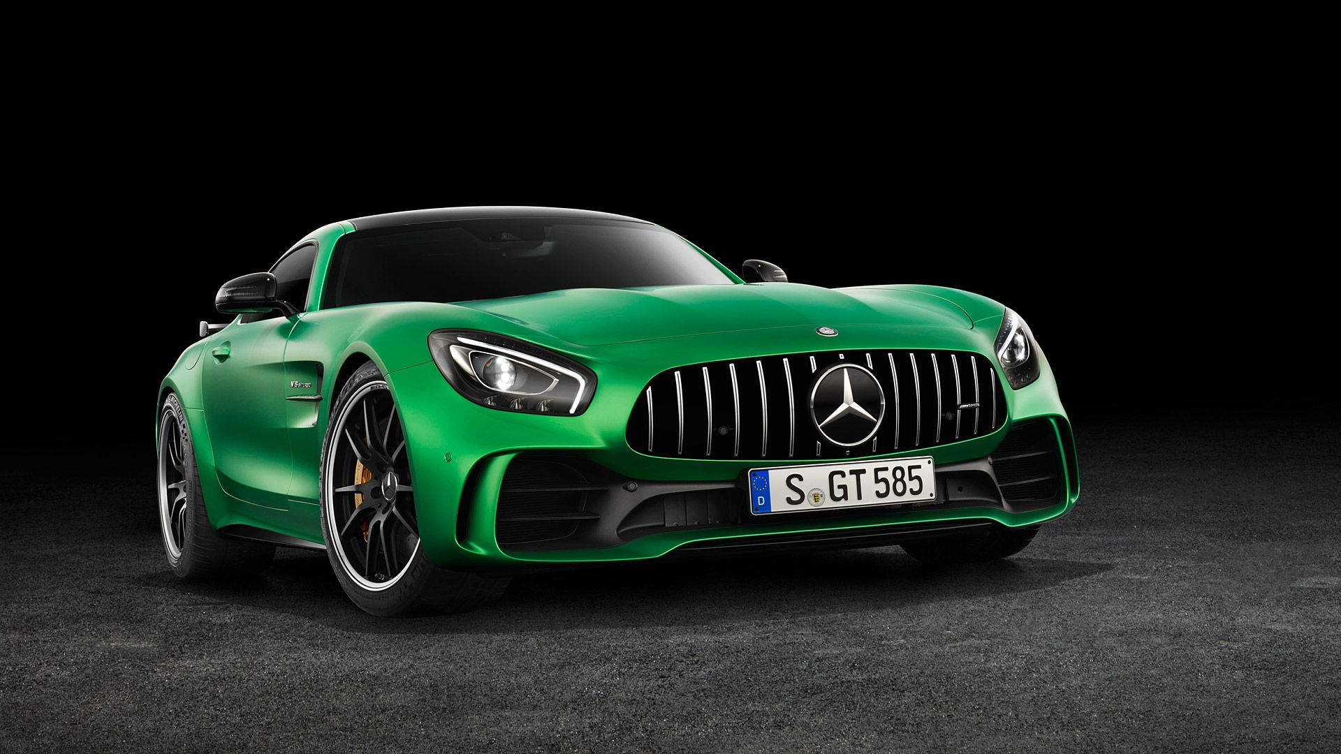 在深色攝影棚地板上，一輛充滿活力的綠色Mercedes-AMG GT S跑車。