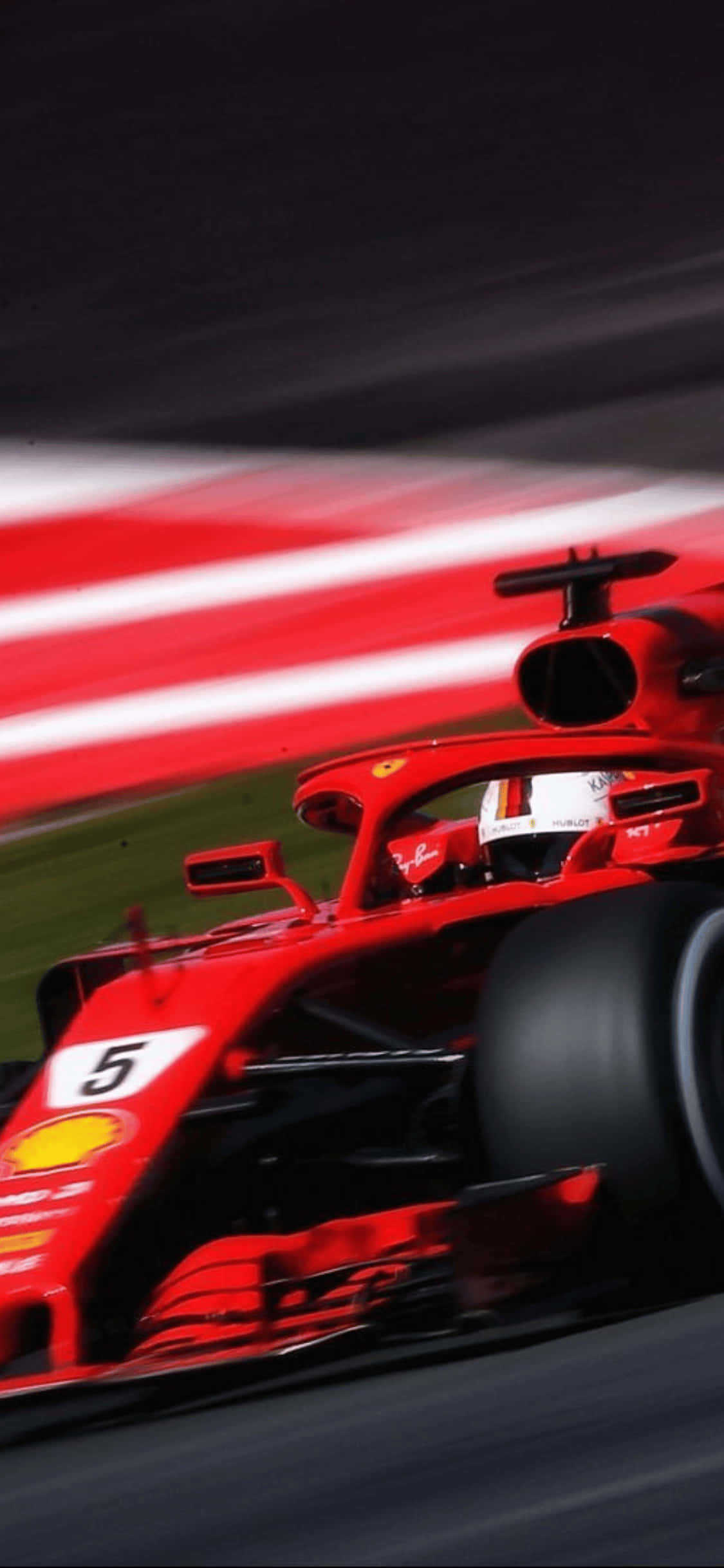 2018年F1賽車iPhone XS背景 壁紙 — 一輛紅色法拉利一級方程式賽車在夜間賽道上高速駛過，帶有動態模糊效果。