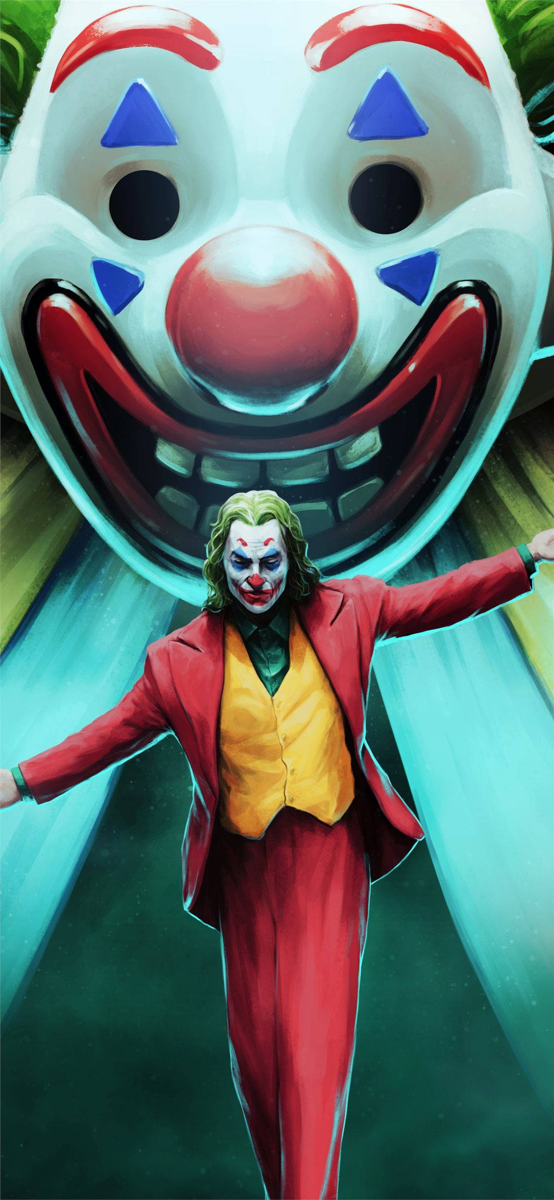 《Joker》2019電影藝術 壁紙 — 一個穿著紅色西裝的威脅性小丑站在一個巨大小丑面具前，面具露出寬闊的笑容，背景是發光的綠色。