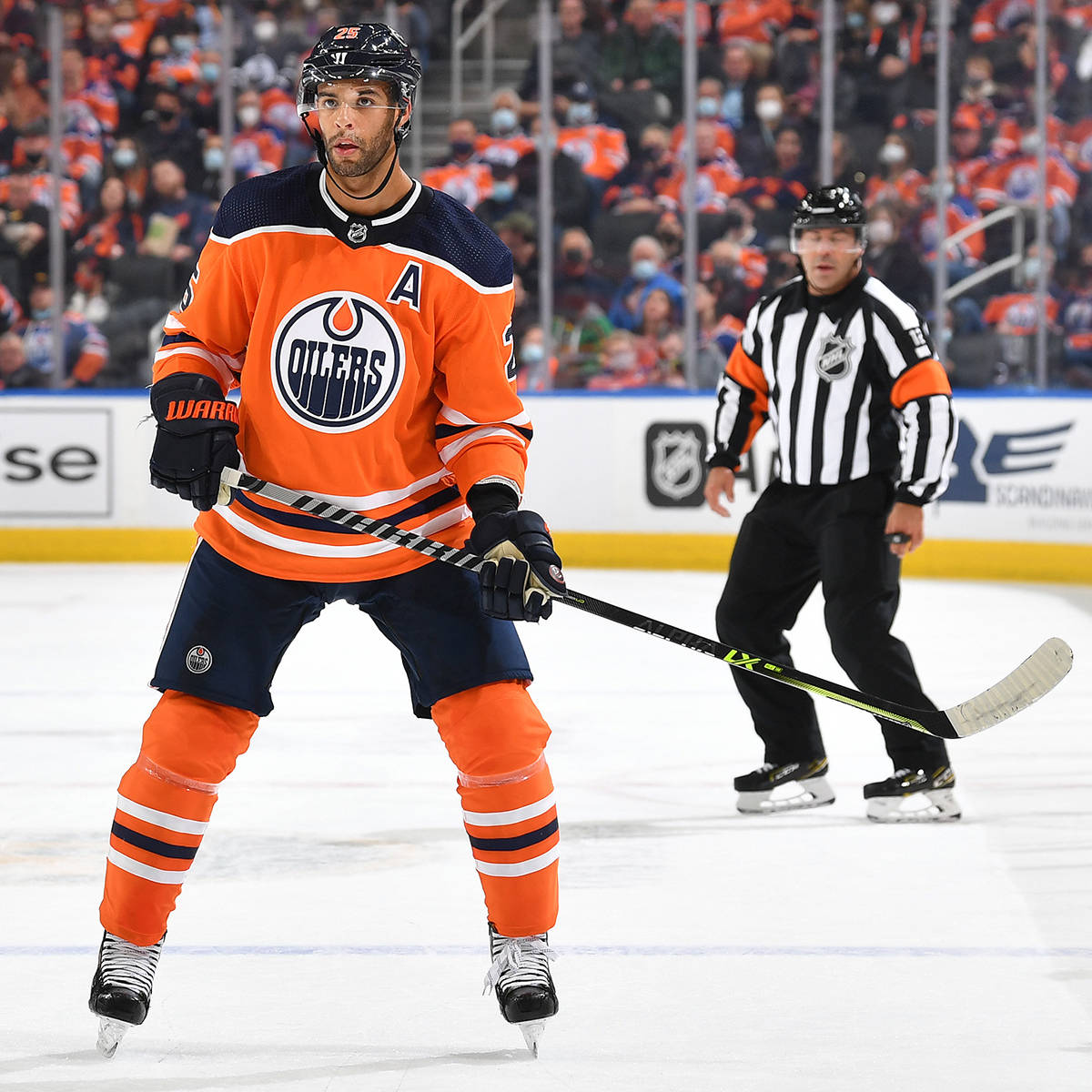 2019年NHL賽事中埃德蒙頓油人隊後衛達內爾·納斯 壁紙 — 一位專注的愛民頓油人冰球球員，身穿橙色和海軍藍裝備，在比賽中持桿滑行，附近有裁判。
