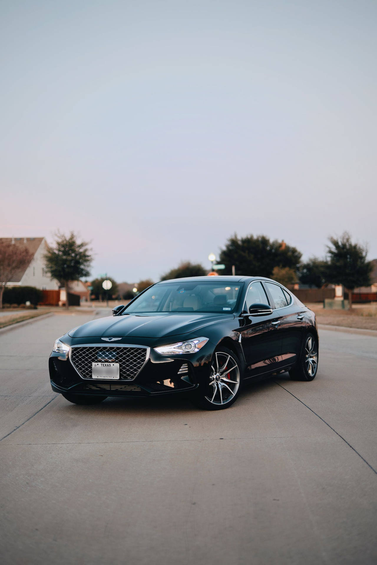 黑色Genesis G70房車停泊在住宅街道上，黃昏時分。