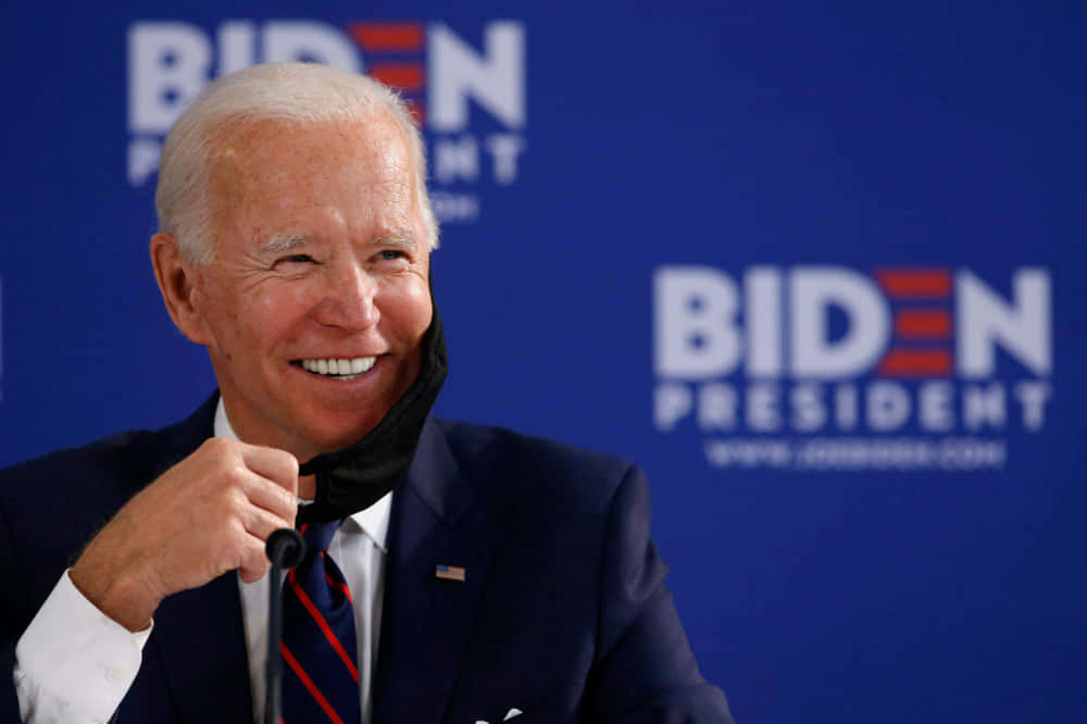 喬·拜登2020年選舉 壁紙 — 喬·拜登在藍色「Biden President」背景的競選活動中，手持口罩，露出燦爛笑容。