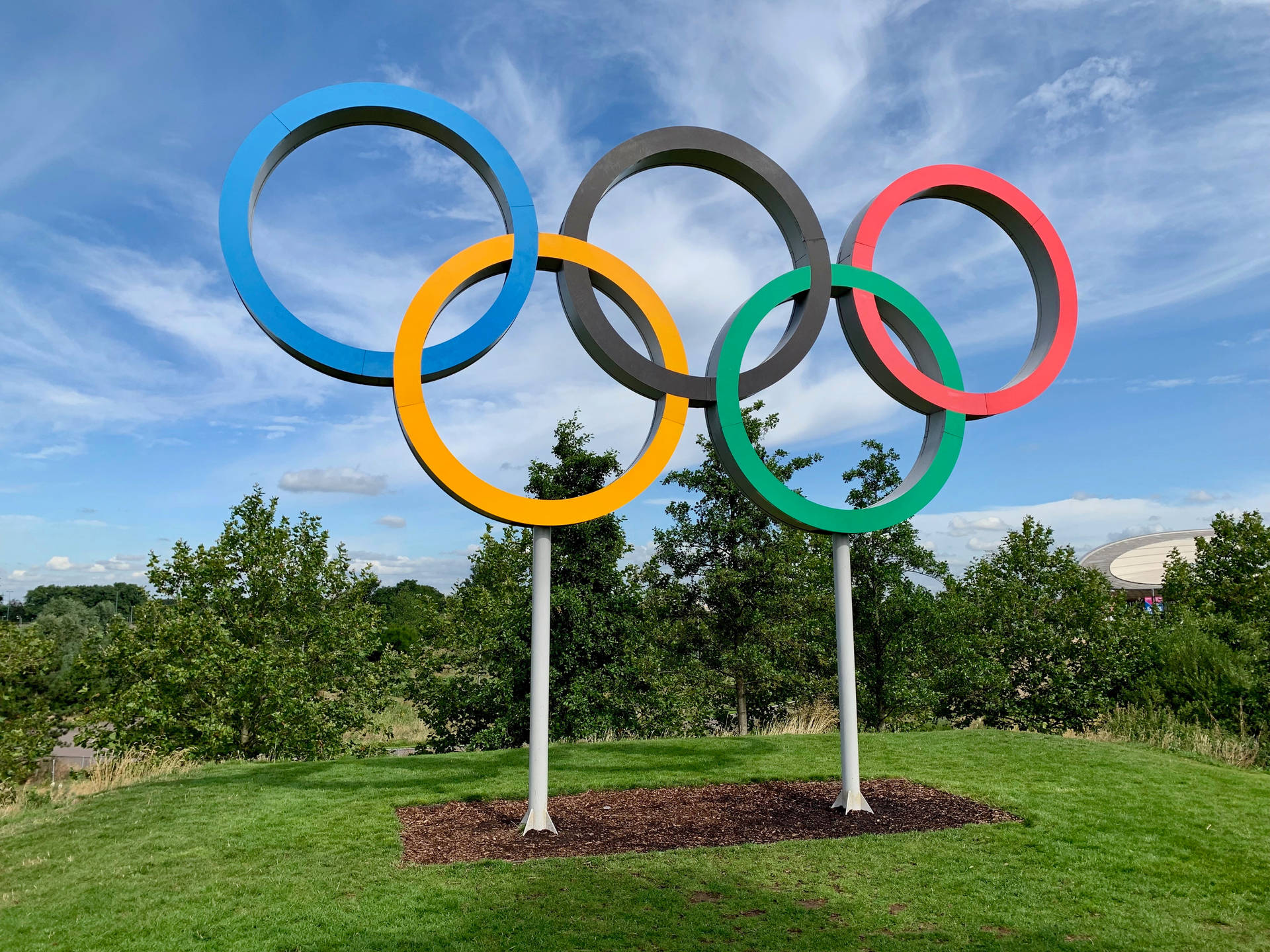 藍天下草地上柱子上的五個奧運五環。