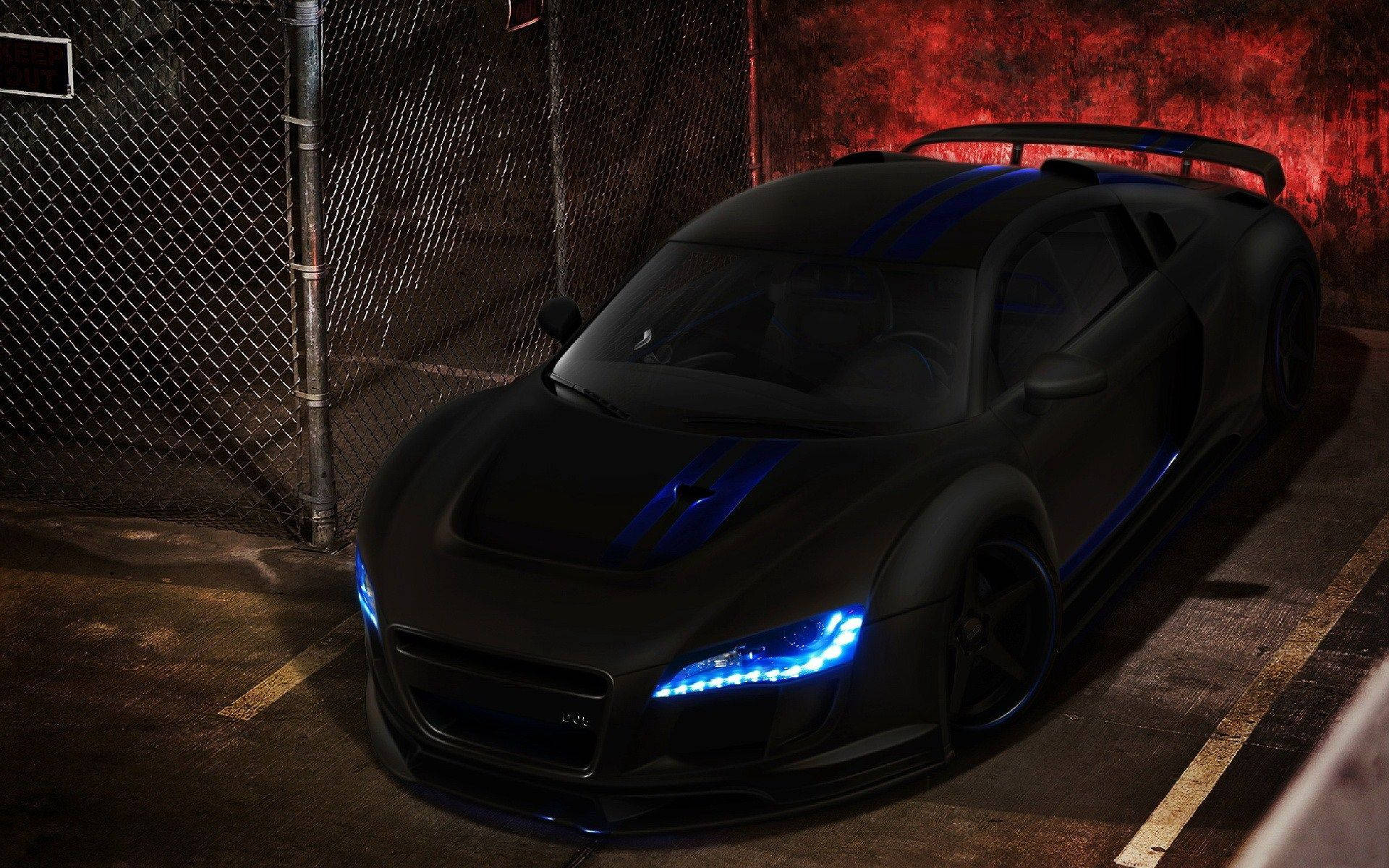 帶藍色燈光的黑色跑車夜間停放在圍欄附近。