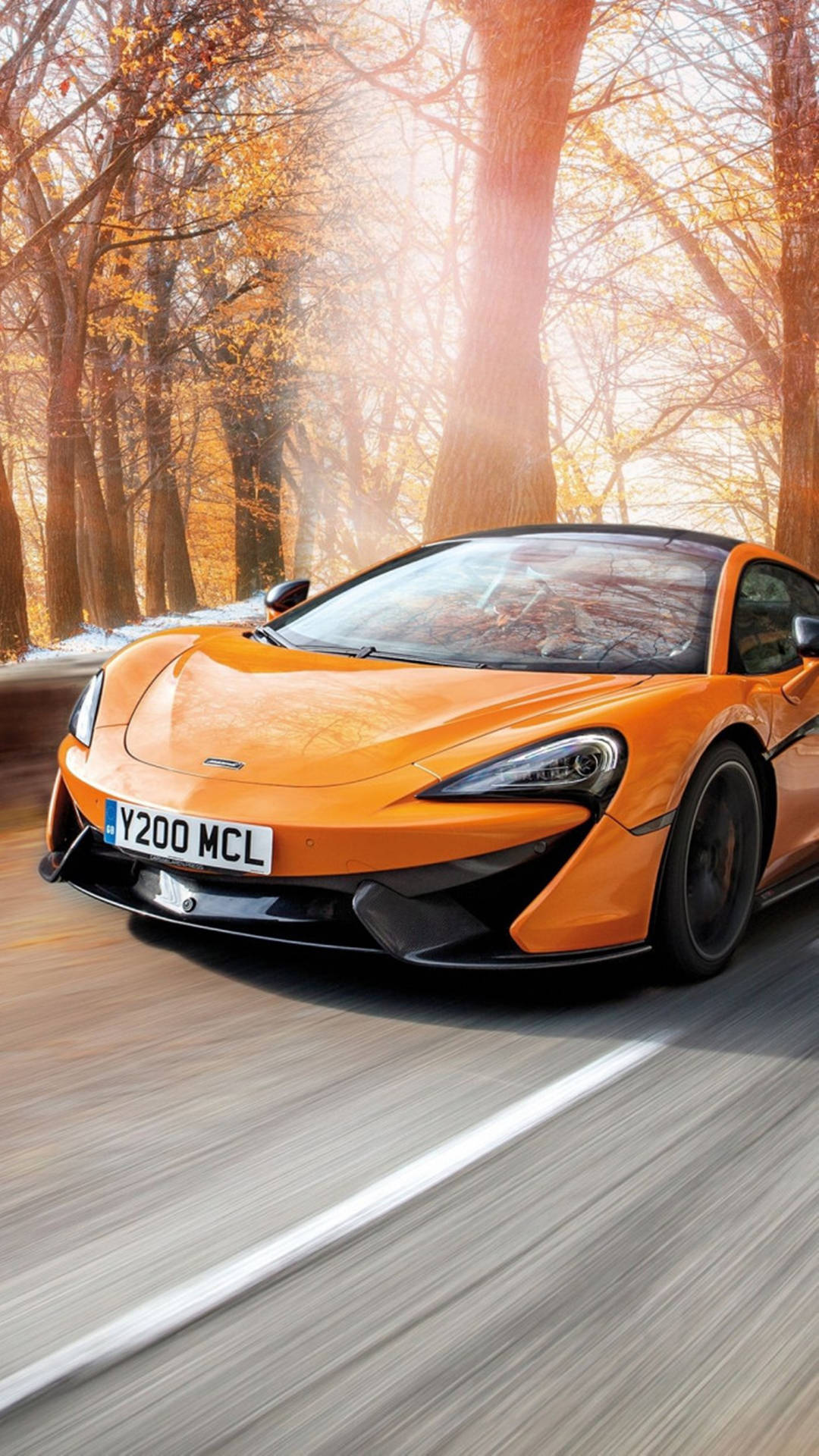 橙色McLaren在秋日森林中於夕陽下疾馳