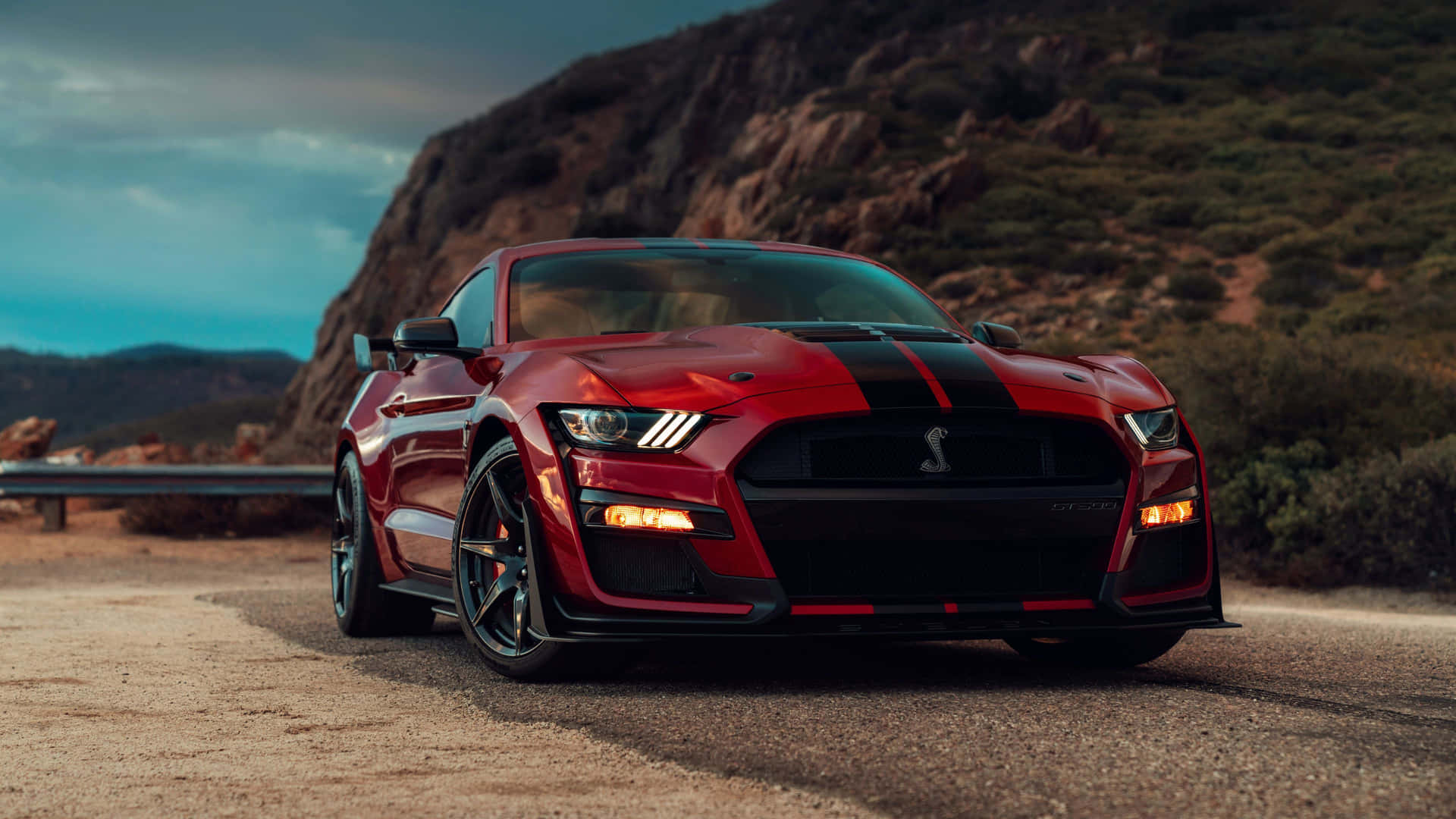 黃昏時分，紅色福特野馬Shelby GT500行駛在山路上。