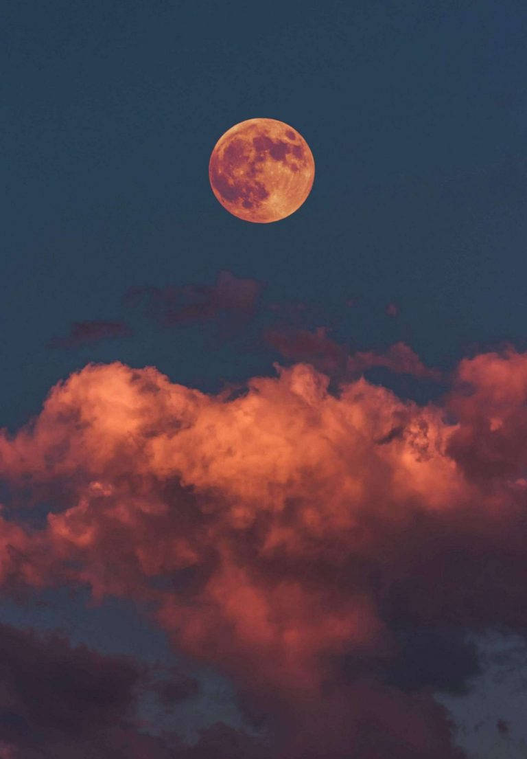 滿月照亮了暮色天空中戲劇性的紅雲。