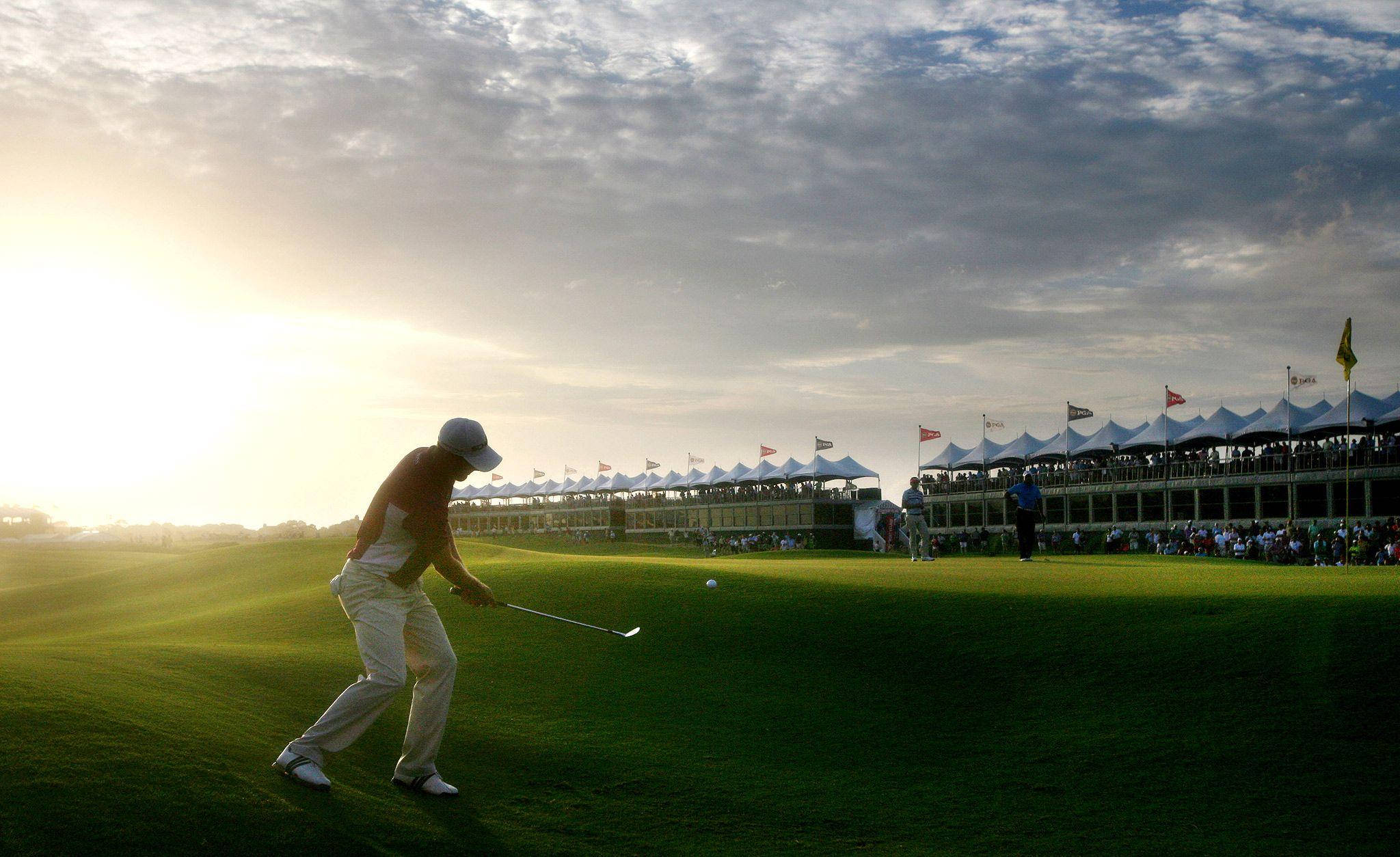 2021 PGA 錦標賽 基亞瓦島 壁紙 — 一名高爾夫球手在日落時揮桿，球場綠草如茵，觀眾在白帳篷下觀看。