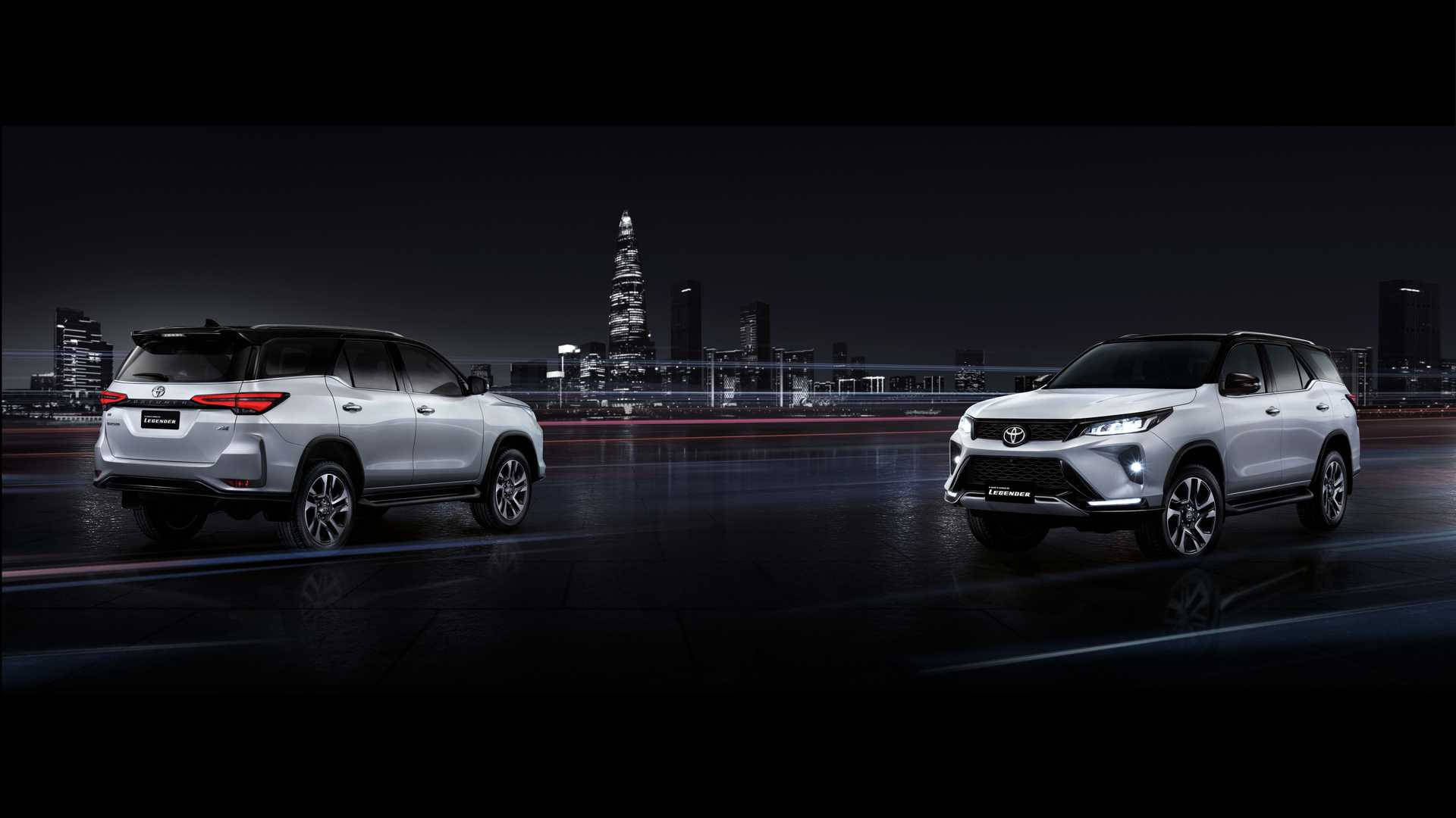 2021豐田Fortuner Legender款 壁紙 — 兩輛銀色SUV在夜間濕滑的城市道路上相對而行，背景是發光的摩天大樓。