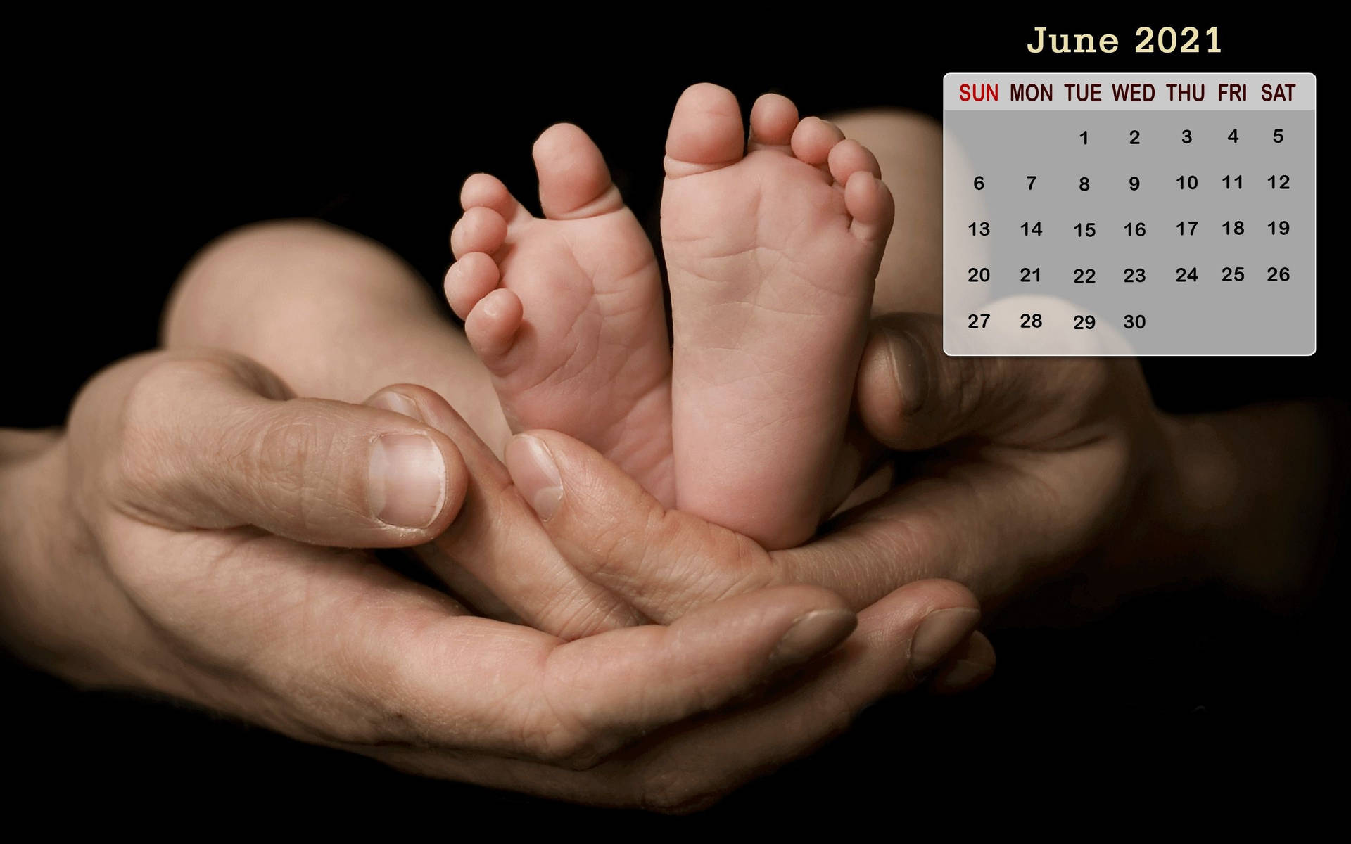 成年人的手托住嬰兒的腳，角落有2021年6月的日曆。