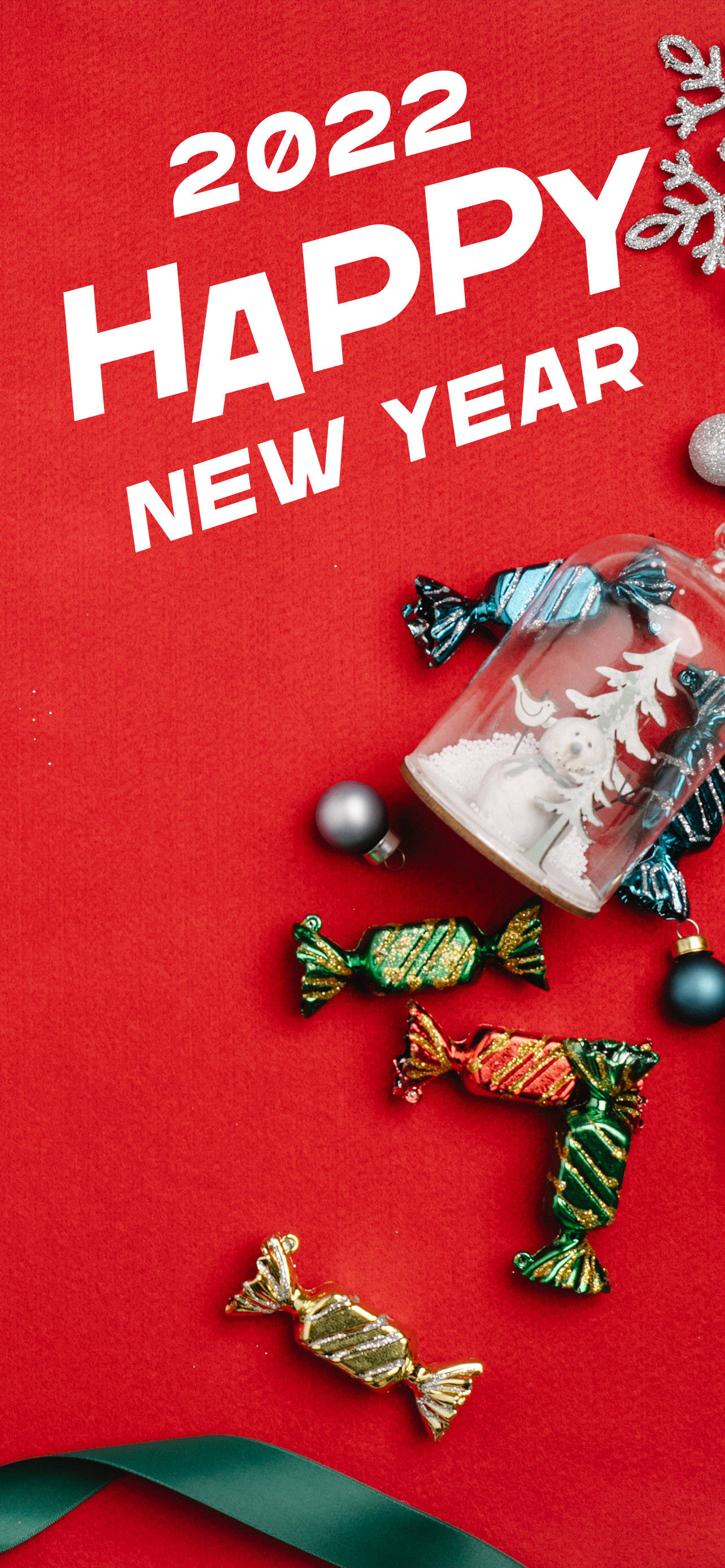 熱情洋溢的2022新年慶祝 壁紙 — 鮮豔的紅色背景，粗體白色文字寫著 2022 HAPPY NEW YEAR，周圍環繞著節日糖果、裝飾品和一個雪球。