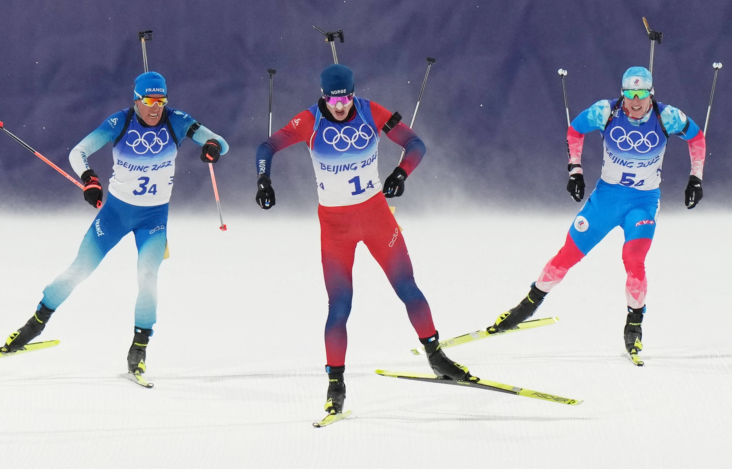 越野滑雪射擊選手約翰內斯·廷格斯·博在2022北京冬季奧運會 壁紙 — 三名身穿鮮豔奧運裝備的冬季兩項運動員，肩上掛著步槍，在雪地中激烈競賽。