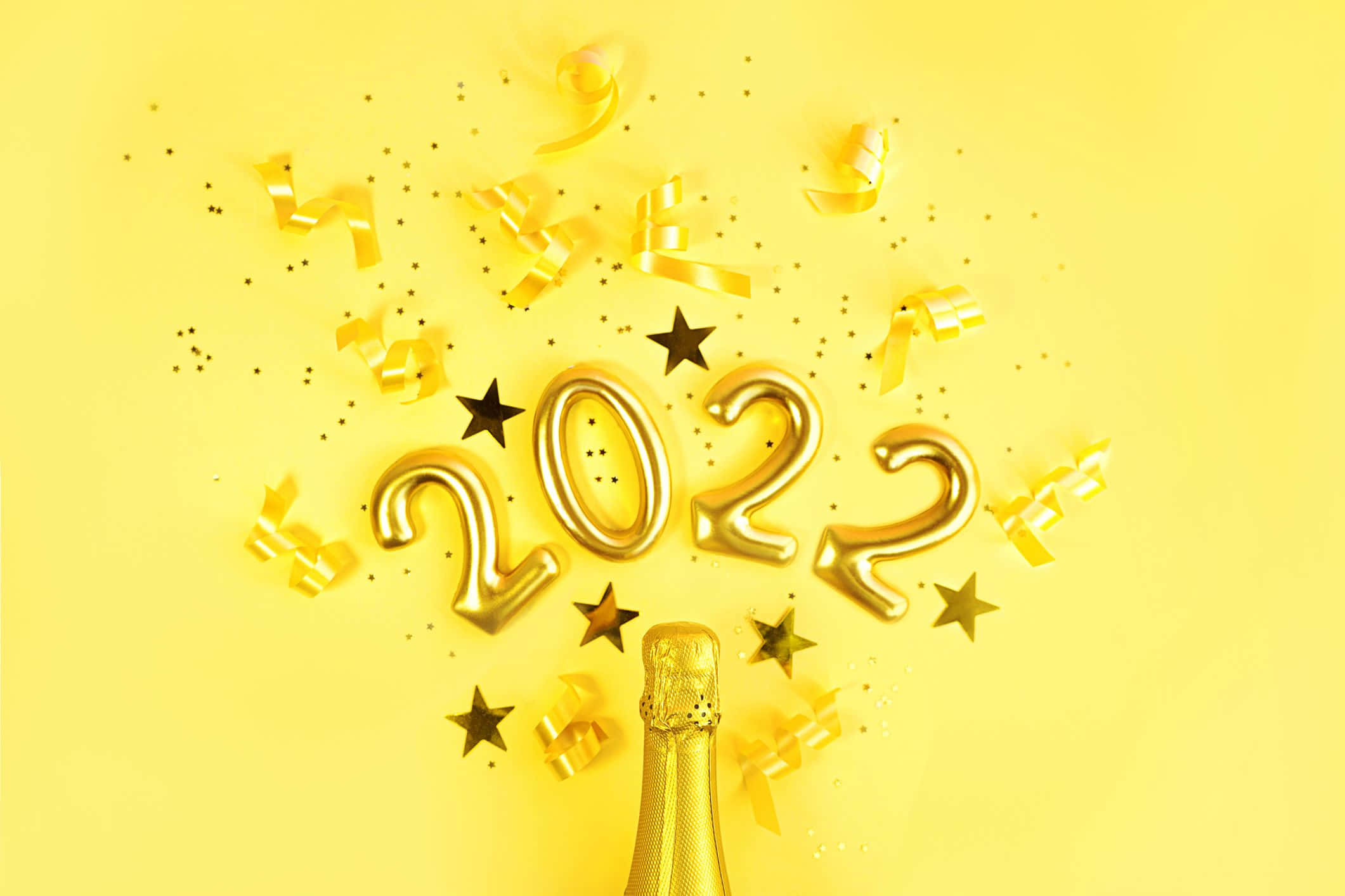 2022黃色藝術圖像 壁紙 — 金色2022氣球在明亮的黃色背景上，在香檳瓶上方爆開，散發出五彩紙屑和星星。