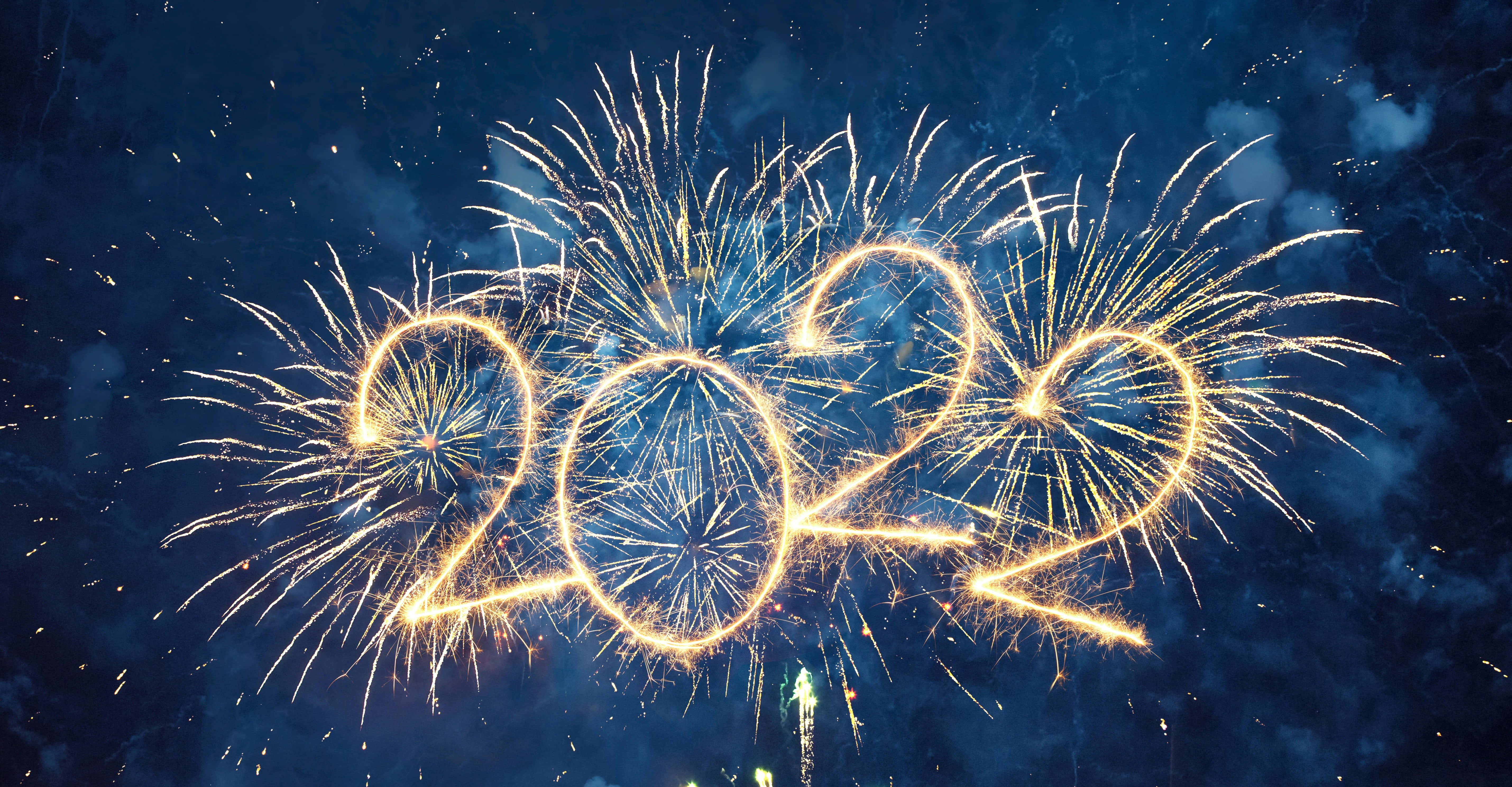 2022新年圖 壁紙 — 金色煙火在深藍色夜空和散落的煙霧中拼出2022。