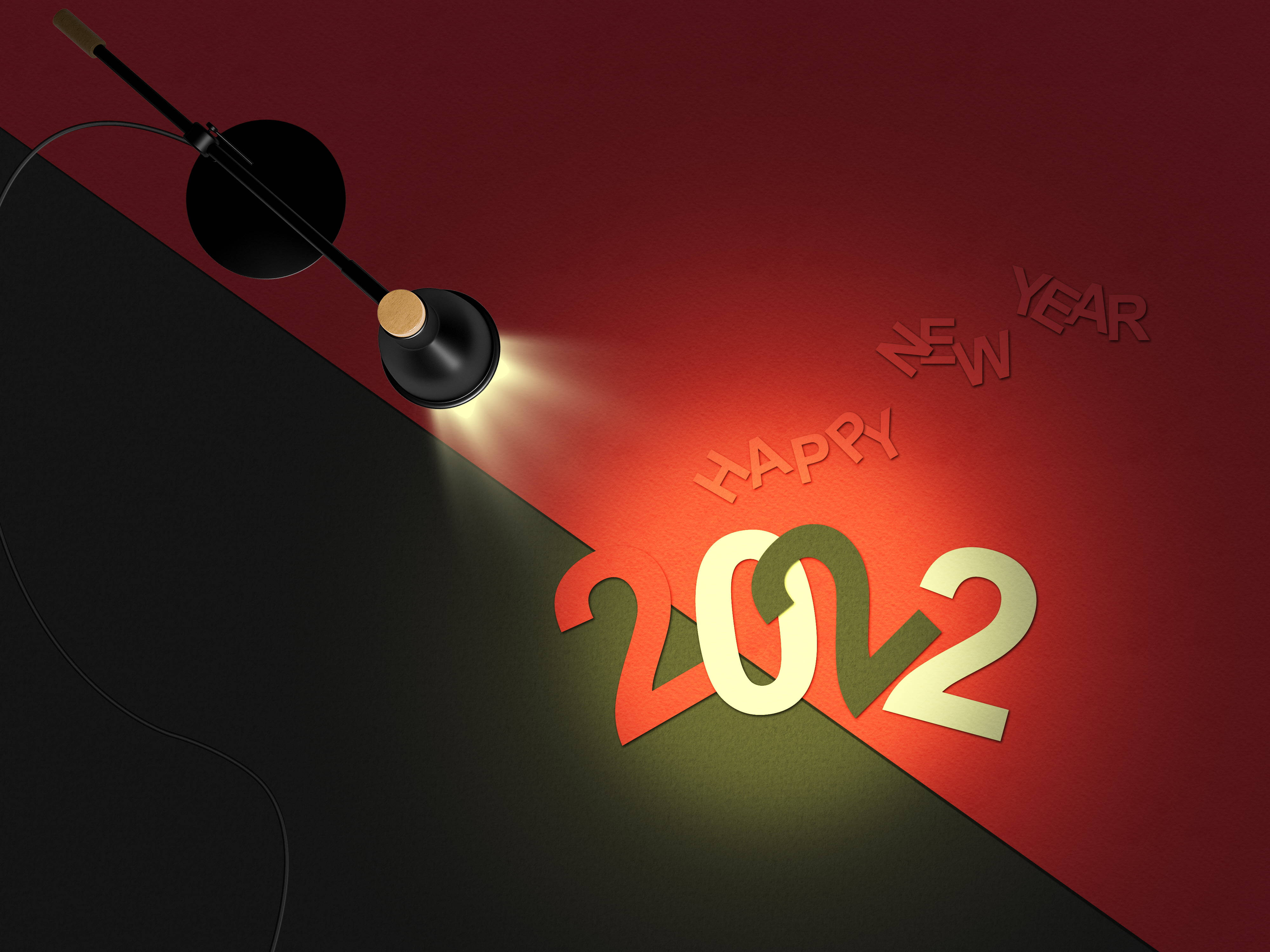 2022新年快樂紅色聚光燈壁紙 壁紙 — 聚光燈照亮了紅色和黑色分割背景上的粗體2022鏤空字母和「HAPPY NEW YEAR」文字。