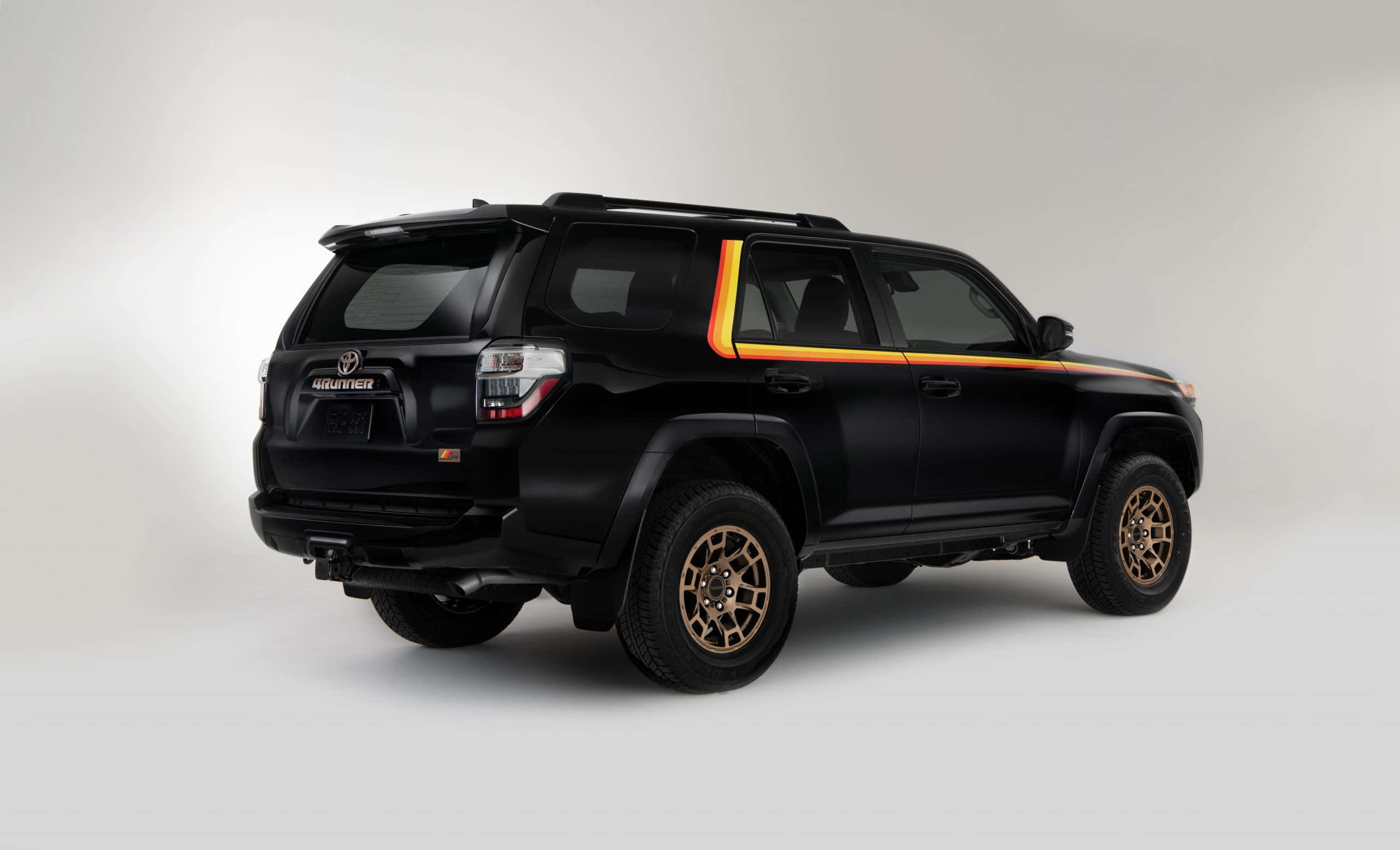 2023 Toyota 4Runner 行動中 — 組合型道路戰士 壁紙 — 一輛時尚的黑色豐田4Runner SUV，帶有金色飾邊和青銅輪轂，在簡約的白色背景下蓄勢待發。