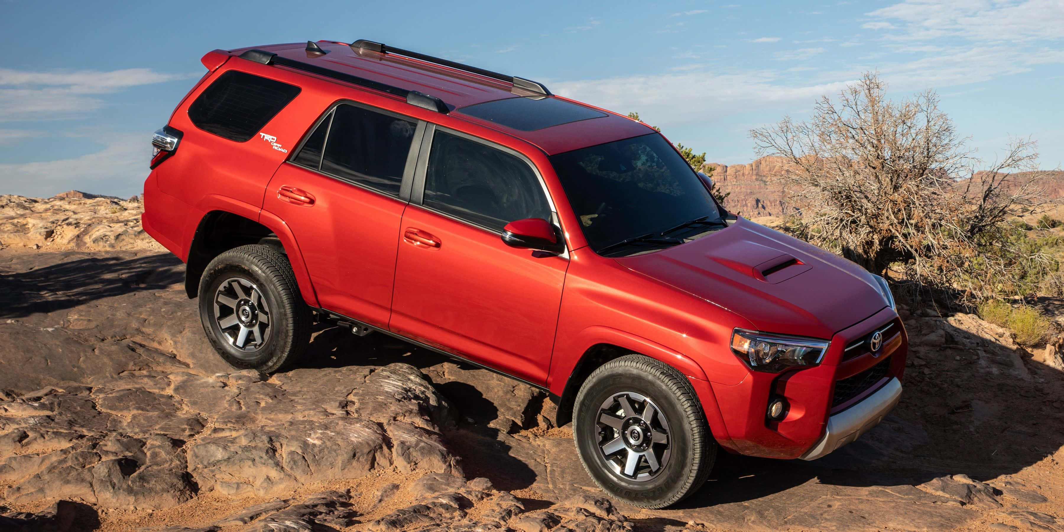 2023 Toyota 4Runner — 准備好迎接任何冒險 壁紙 — 一輛鮮紅色的豐田4Runner SUV自信地停在崎嶇的沙漠岩石上，背景是清澈的藍天。
