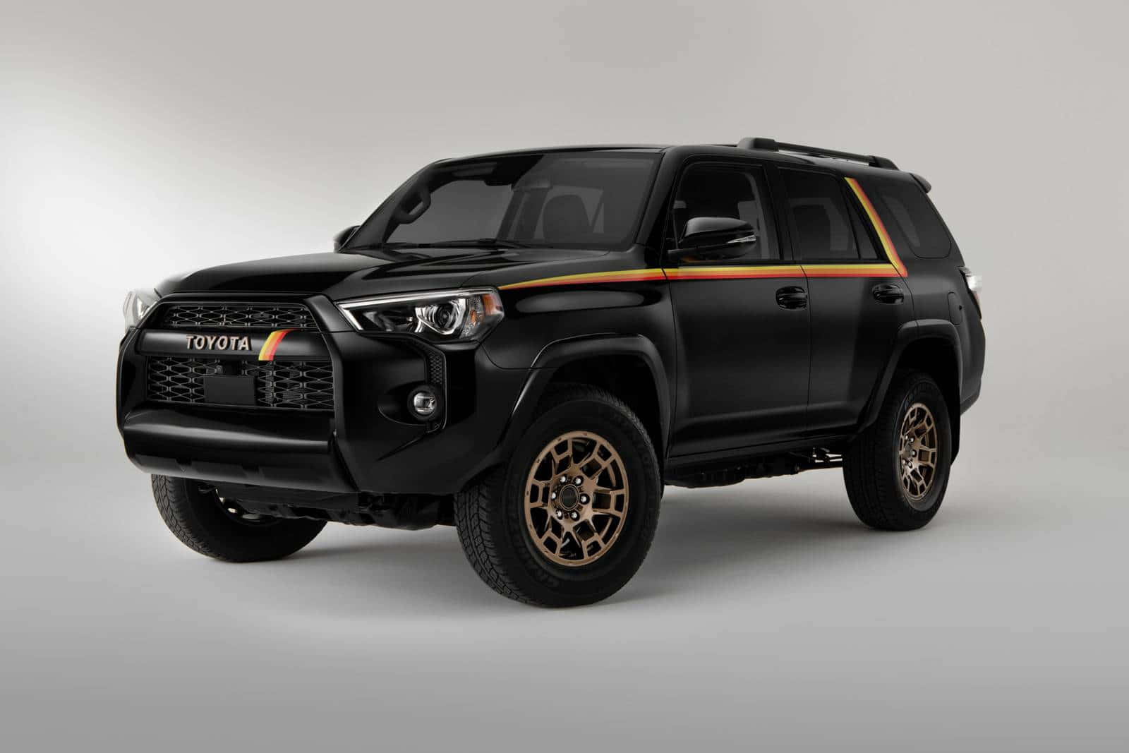 2023 Toyota 4Runner：為冒險而生的性能與風格 壁紙 — 一輛啞光黑色豐田4Runner SUV，配備金色飾條和堅固輪胎，在灰色工作室背景前擺拍。