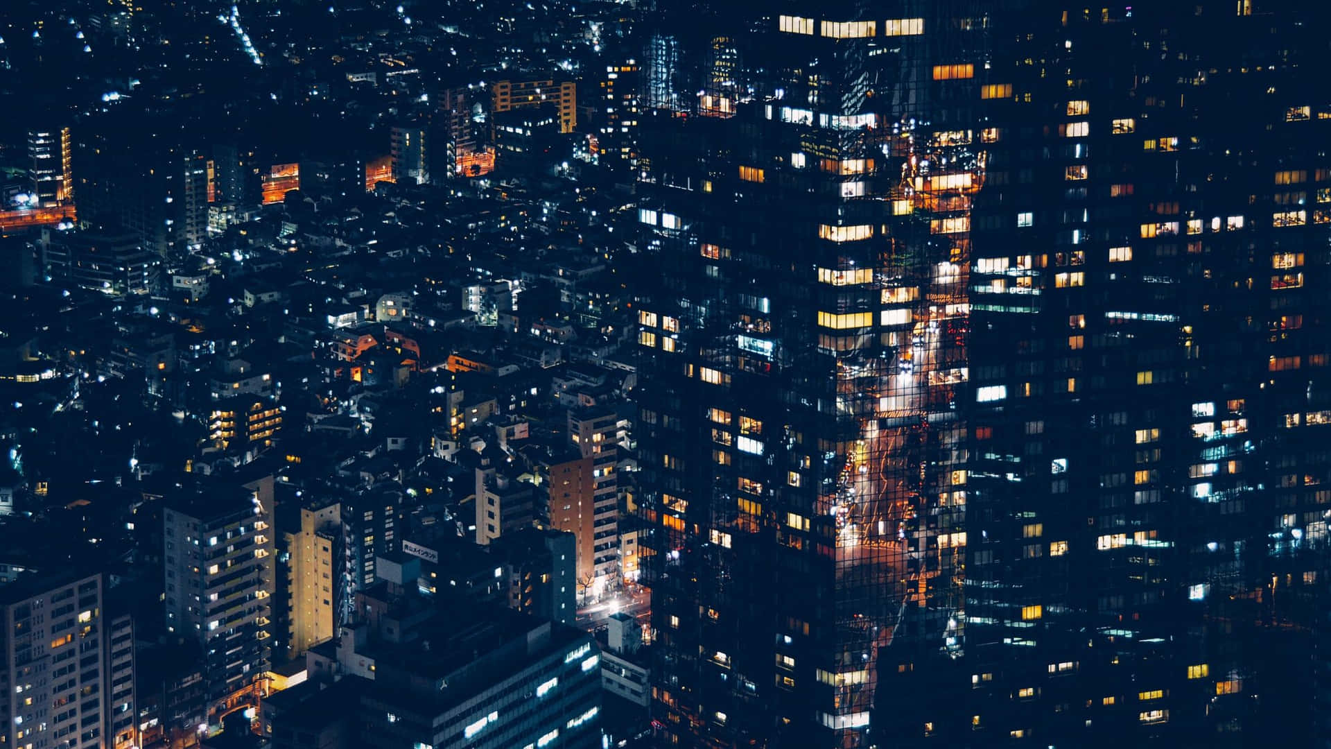 從鳥瞰角度看到的夜間城市景觀，帶有發光的窗戶和明亮的街道。