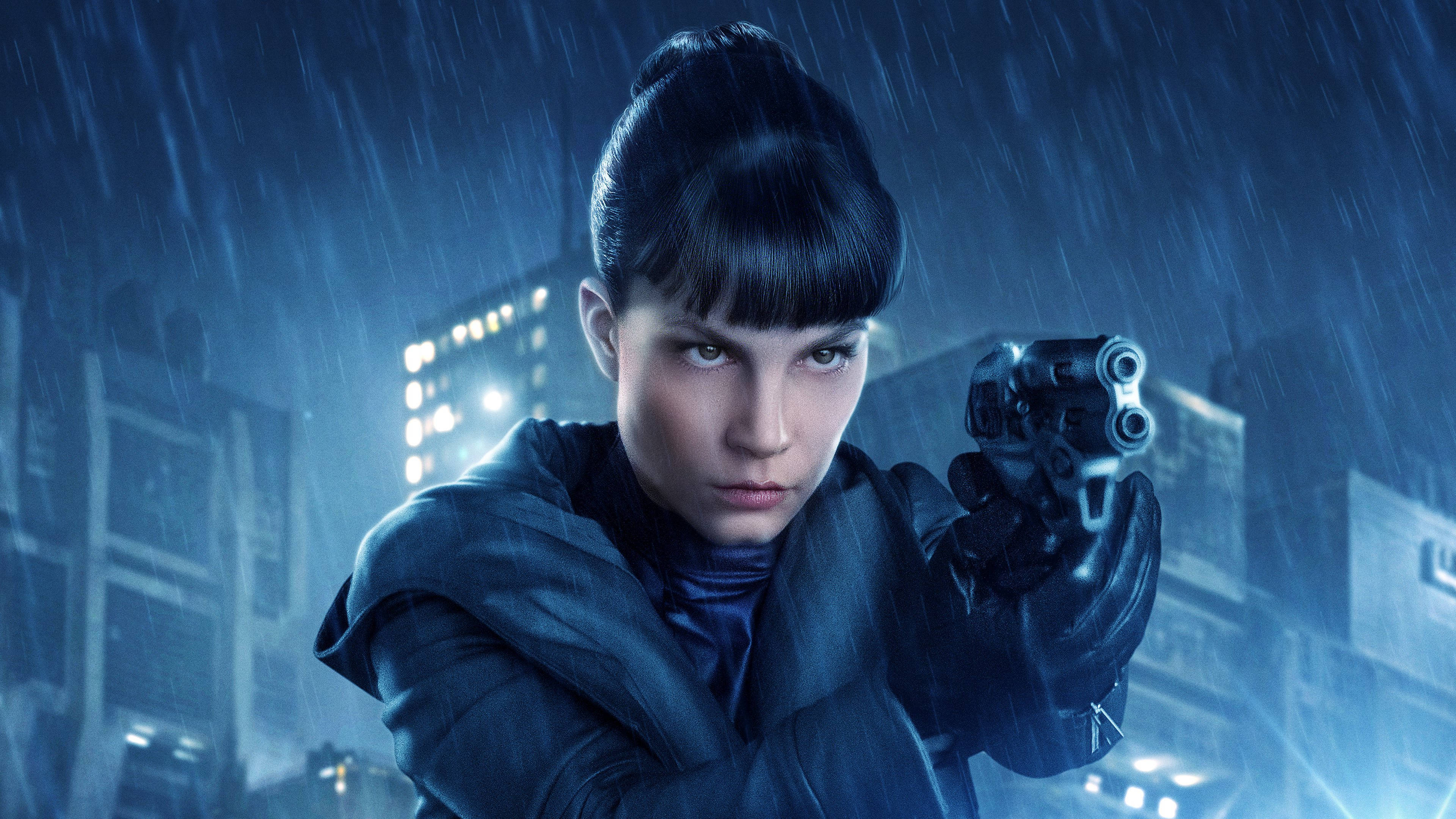 《銀翼殺手2049》露芙雨中持槍 4K 壁紙 — 一個堅定的女人穿著深色外套，在霓虹燈照亮的城市夜景中，在傾盆大雨中瞄準左輪手槍。