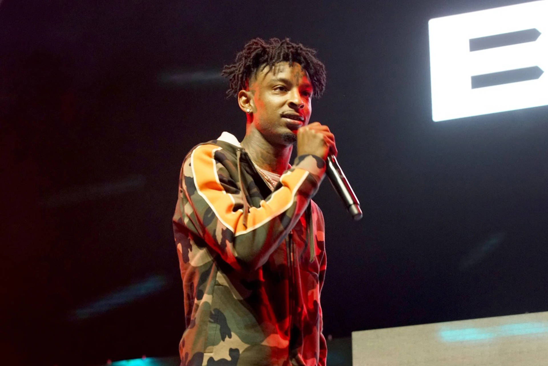 21 Savage 2017 BET 經驗音樂節 壁紙 — 一位留著辮子的男饒舌歌手在紅色舞台燈光下拿著麥克風表演。