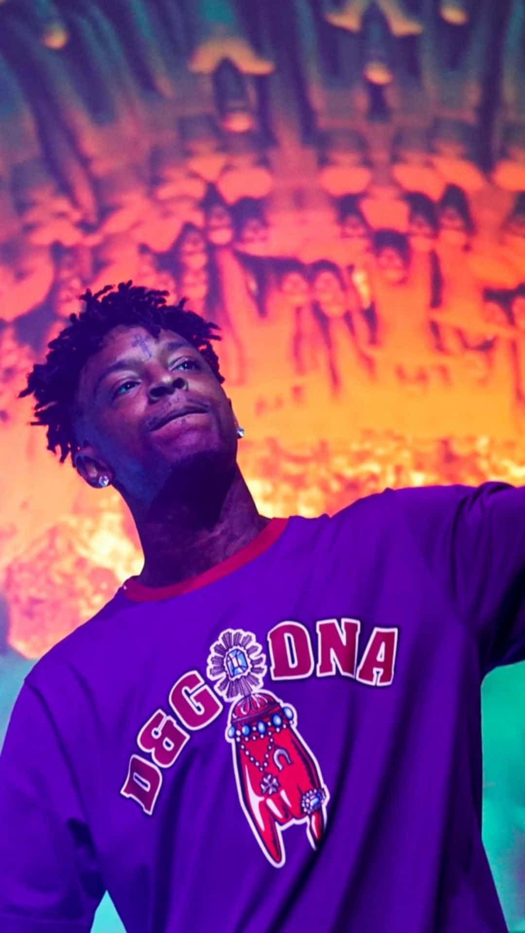 21 Savage — 嘻哈音樂界的 prolific 錄音藝術家 壁紙 — 一名穿著紫色D&G DNA衛衣的男子在充滿活力的橙色和藍綠色音樂會背景及模糊的人群中向上微笑。