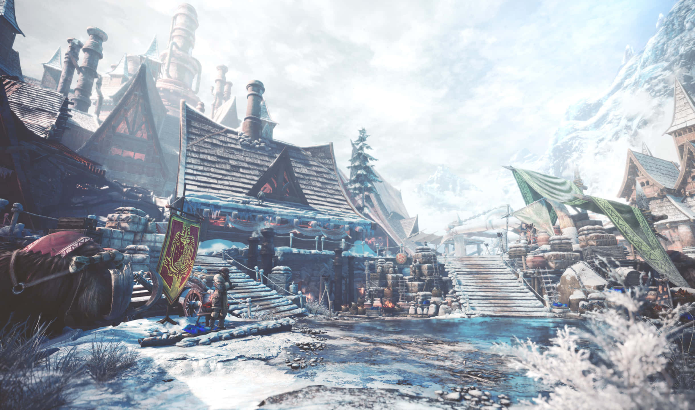 2440x1440 Monster Hunter World 山腳屋舍背景 壁紙 — 一個被雪覆蓋的夢幻村莊，坐落在山脈中，有木製建築和結冰的河流，天空多雲。