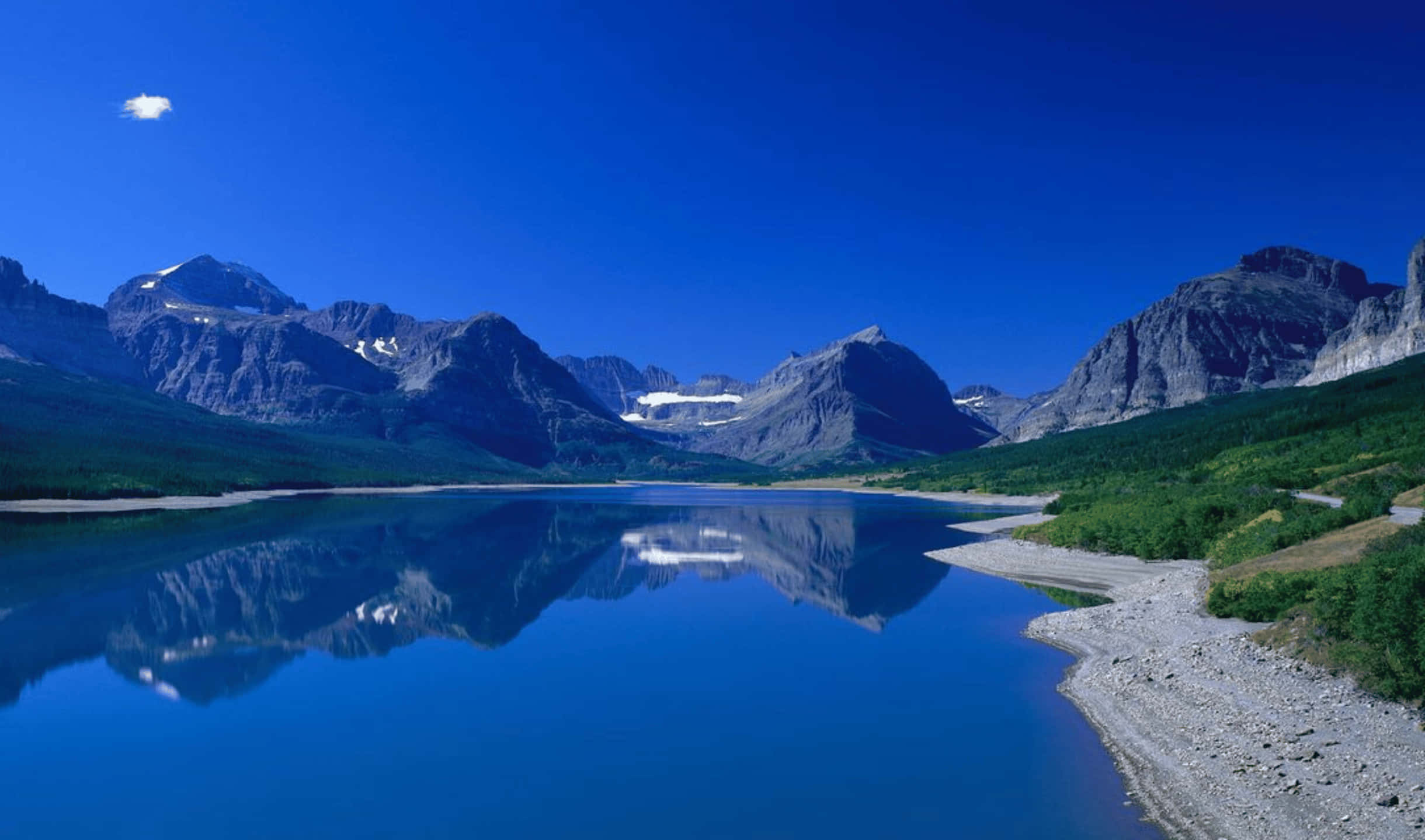 2440x1440 水晶湖景監視器背景 壁紙 — 寧靜的高山湖泊映照出鋸齒狀的雪山，天空湛藍，只有一朵雲。