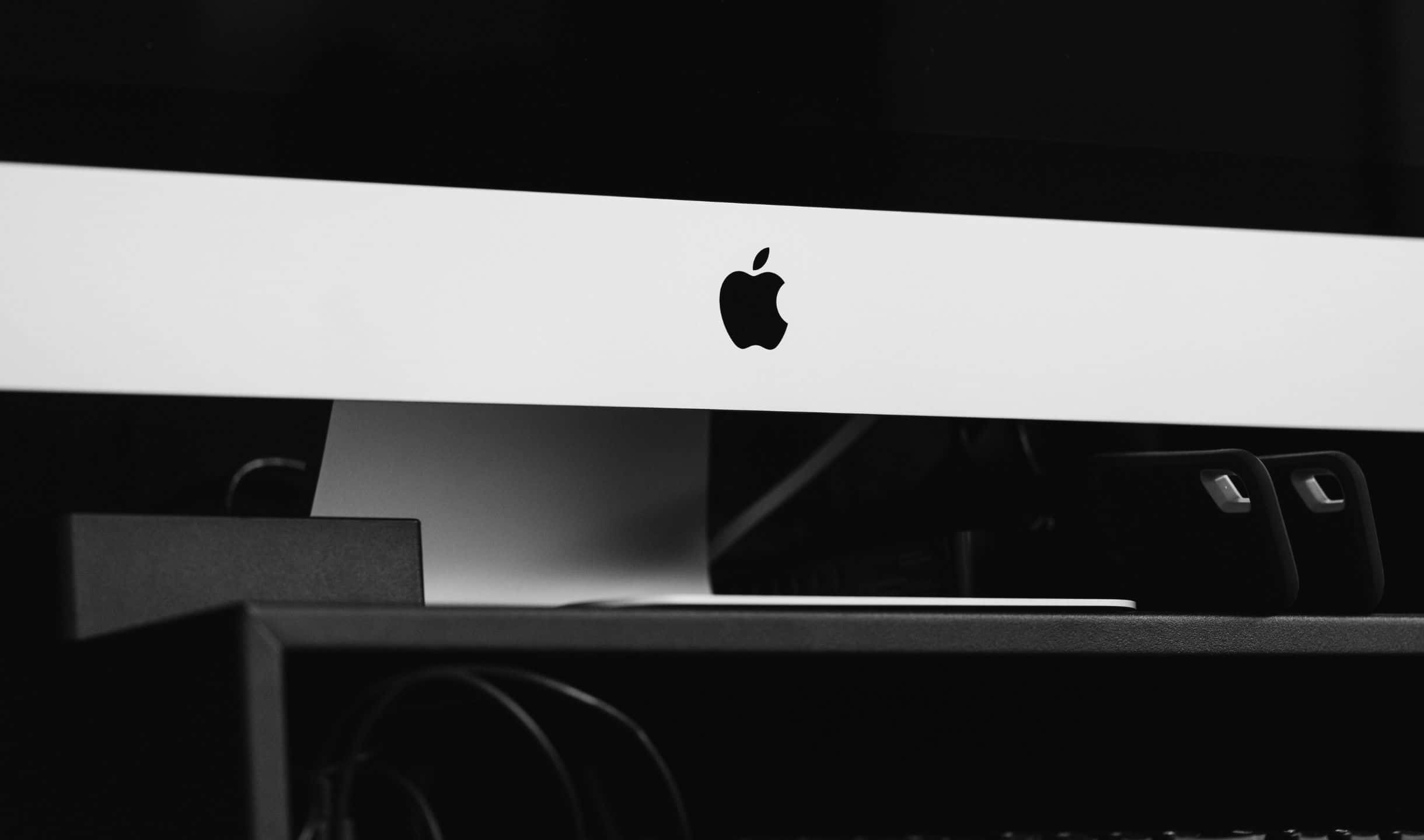 2440x1440 蘋果 iMac 標誌背景 壁紙 — 一部 Apple iMac 的極簡黑白特寫，其標誌性標誌位於纖薄的白色邊框中央。
