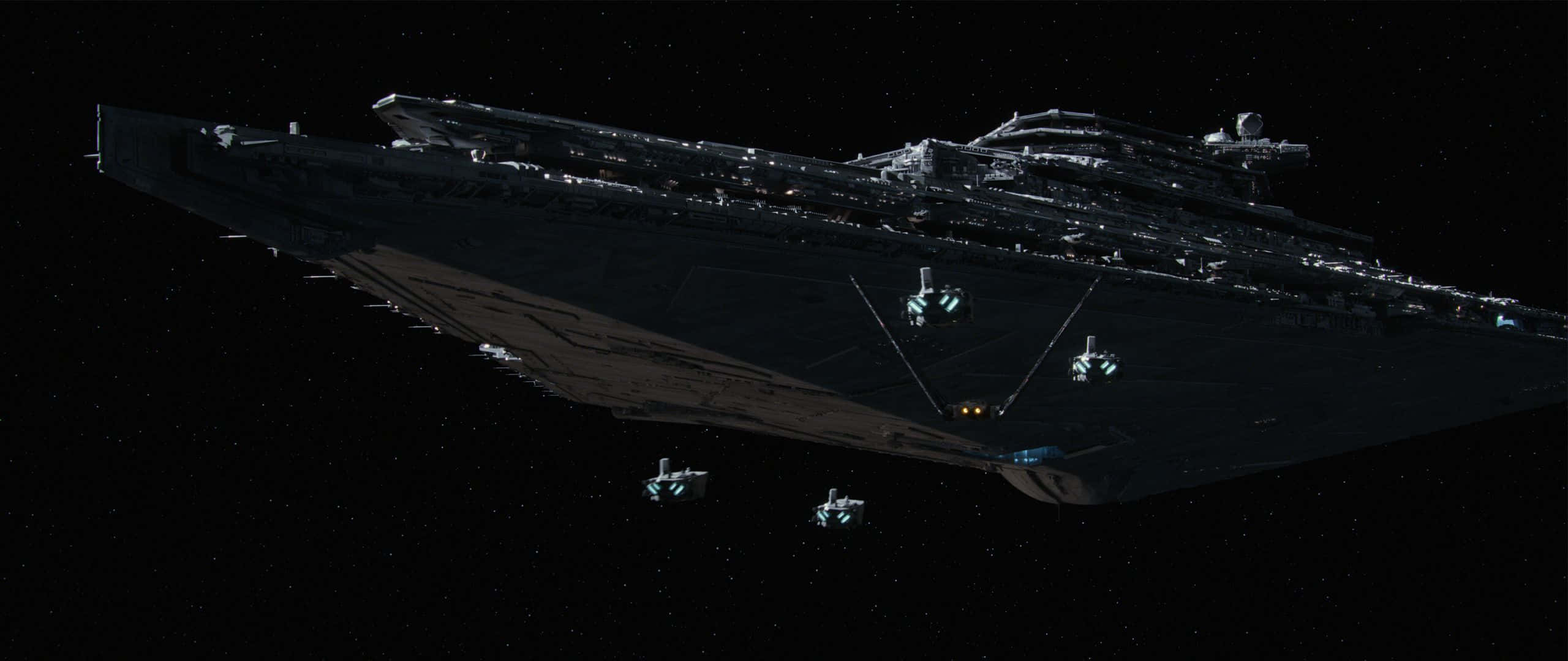 星際大戰 2560 X 1080 第一秩序艦隊 壁紙 — 一艘巨大的黑暗星際毀滅者潛伏在深空中，帶有發光的燈光和小型飛船在星場附近。