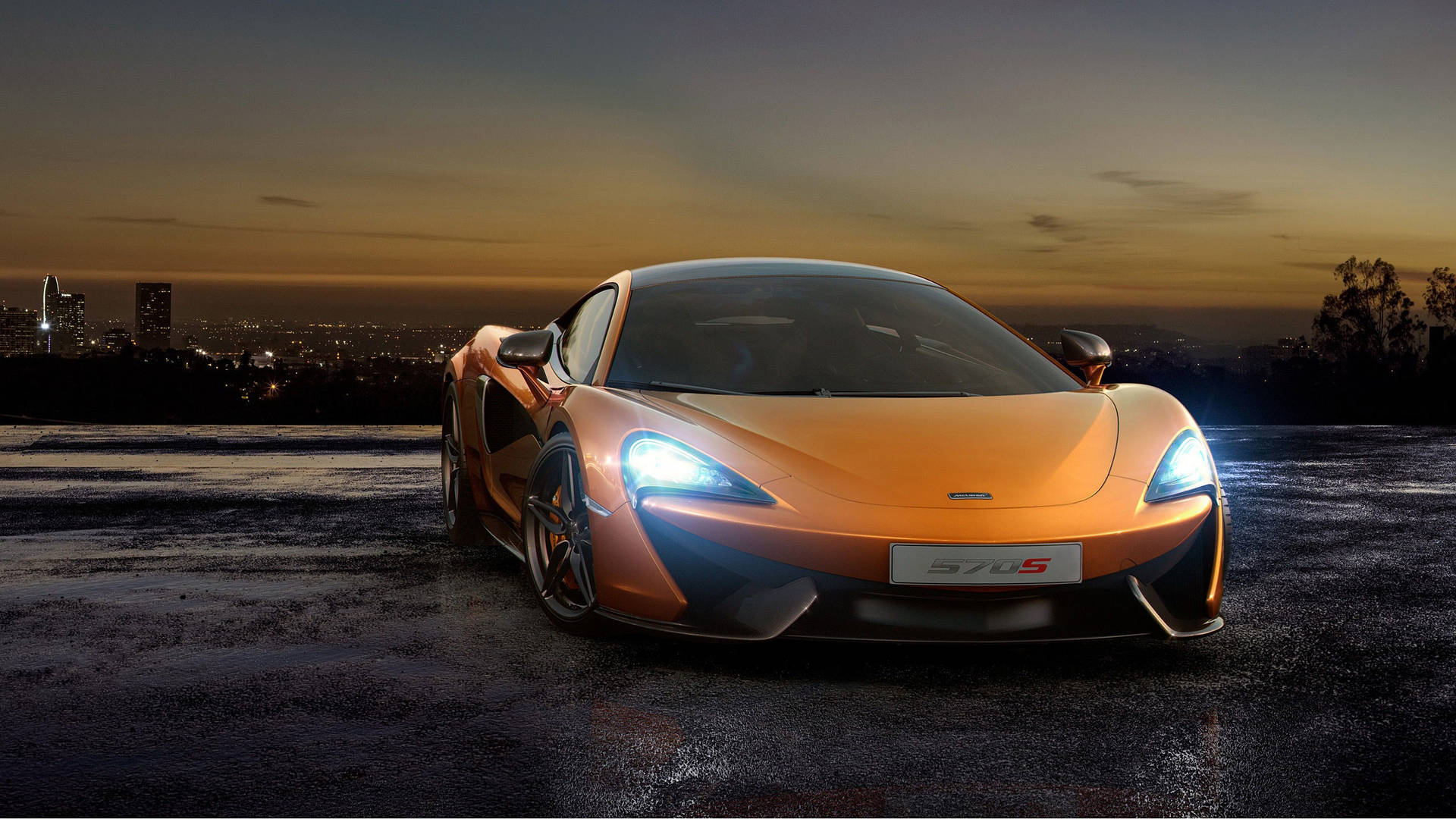 橙色McLaren 570S跑車在暮色中停在濕漉漉的路面上，背後是城市燈光。
