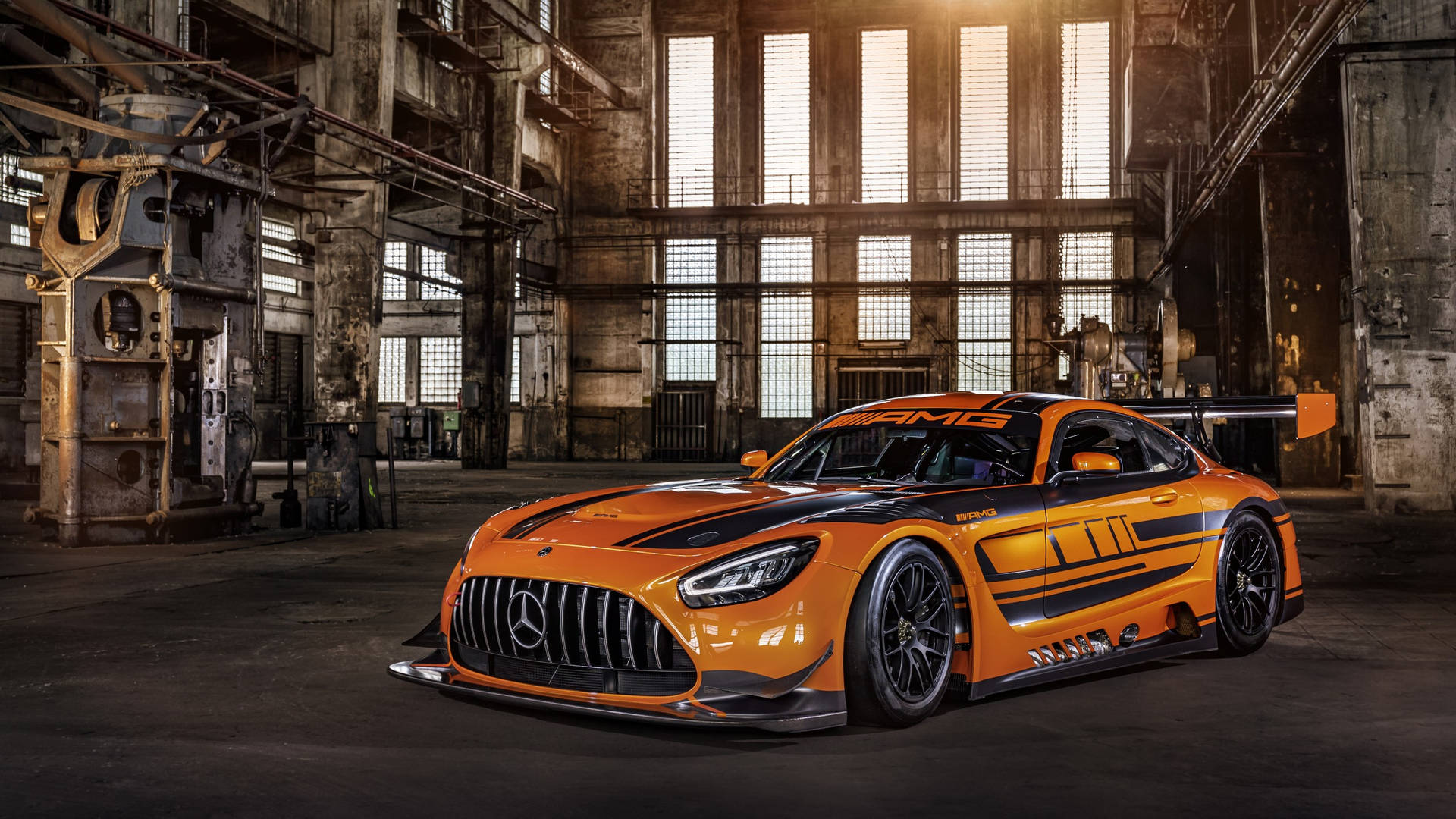 日落時分，生鏽的工業倉庫中的橙色 Mercedes-AMG GT3 賽車。