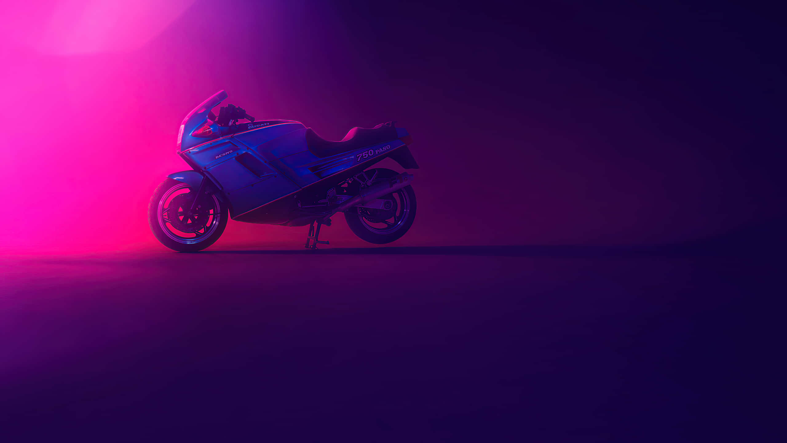 2560x1440 蘇州杜卡迪機車 壁紙 — 一輛時尚的運動摩托車沐浴在充滿活力的粉紅色和紫色工作室燈光下，在黑暗的地板上投下戲劇性的陰影。