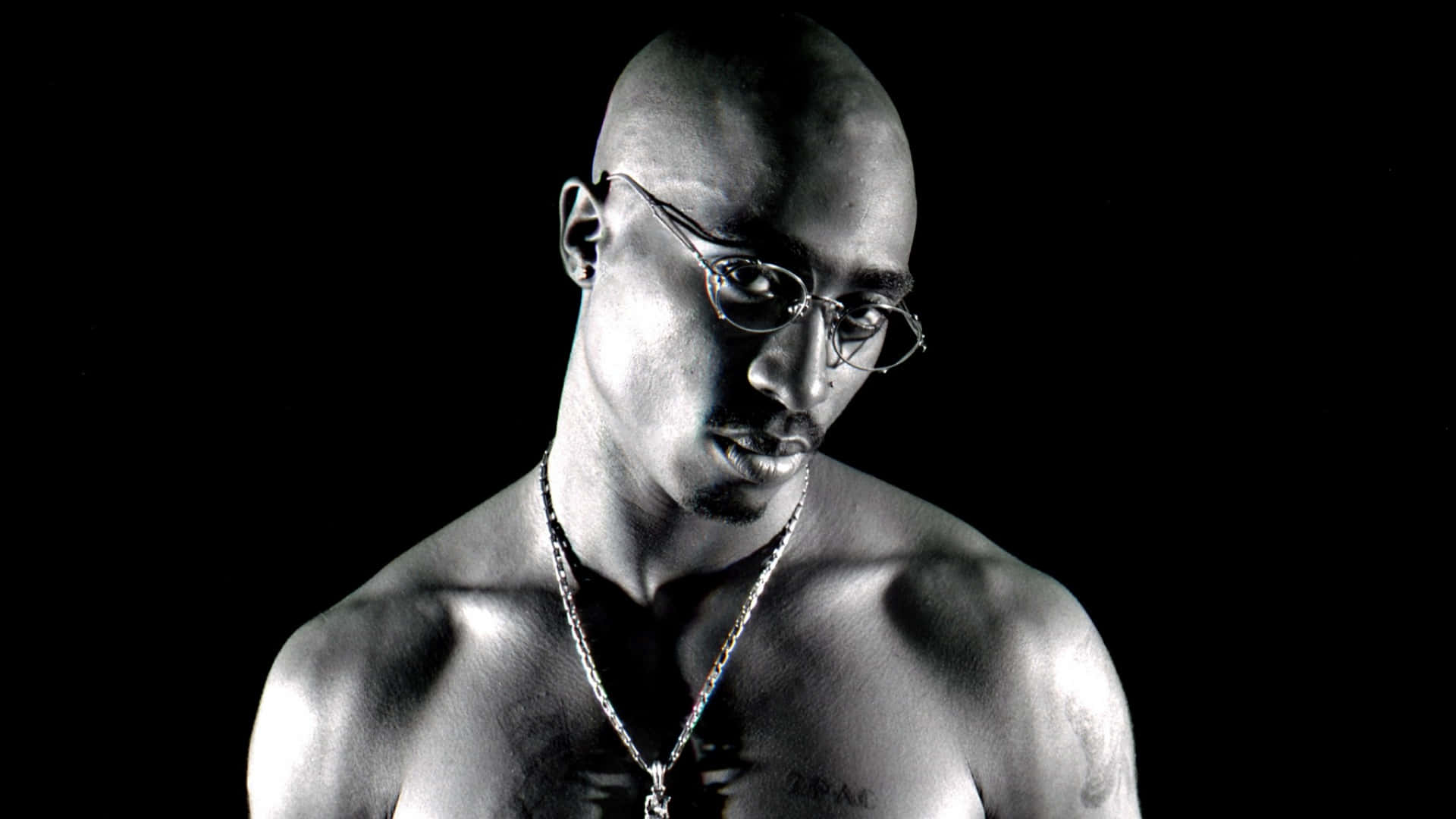 Tupac Shakur 在黑白工作室肖像中戴著眼鏡和鏈條。