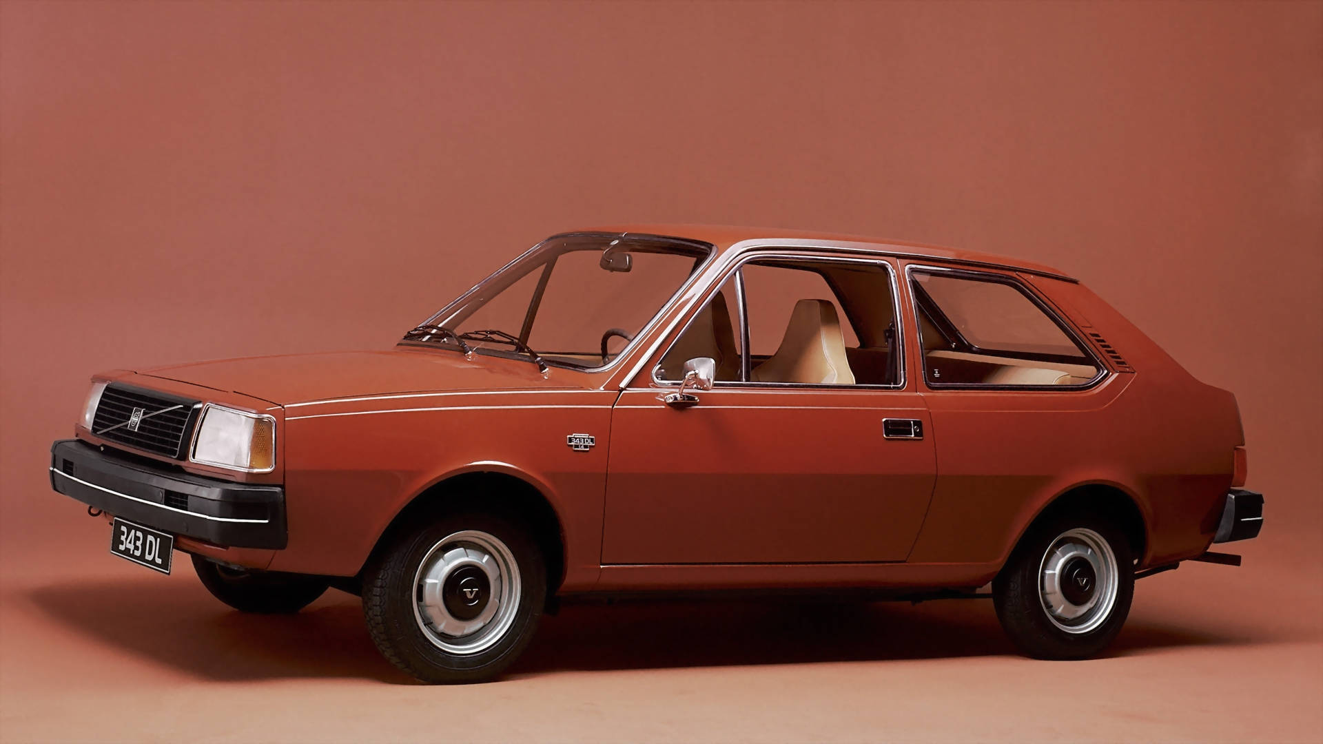 300系列紅色Volvo iPhone相片 壁紙 — 一輛復古鏽橙色掀背車在工作室中擺姿勢，搭配相襯的背景和柔和燈光。