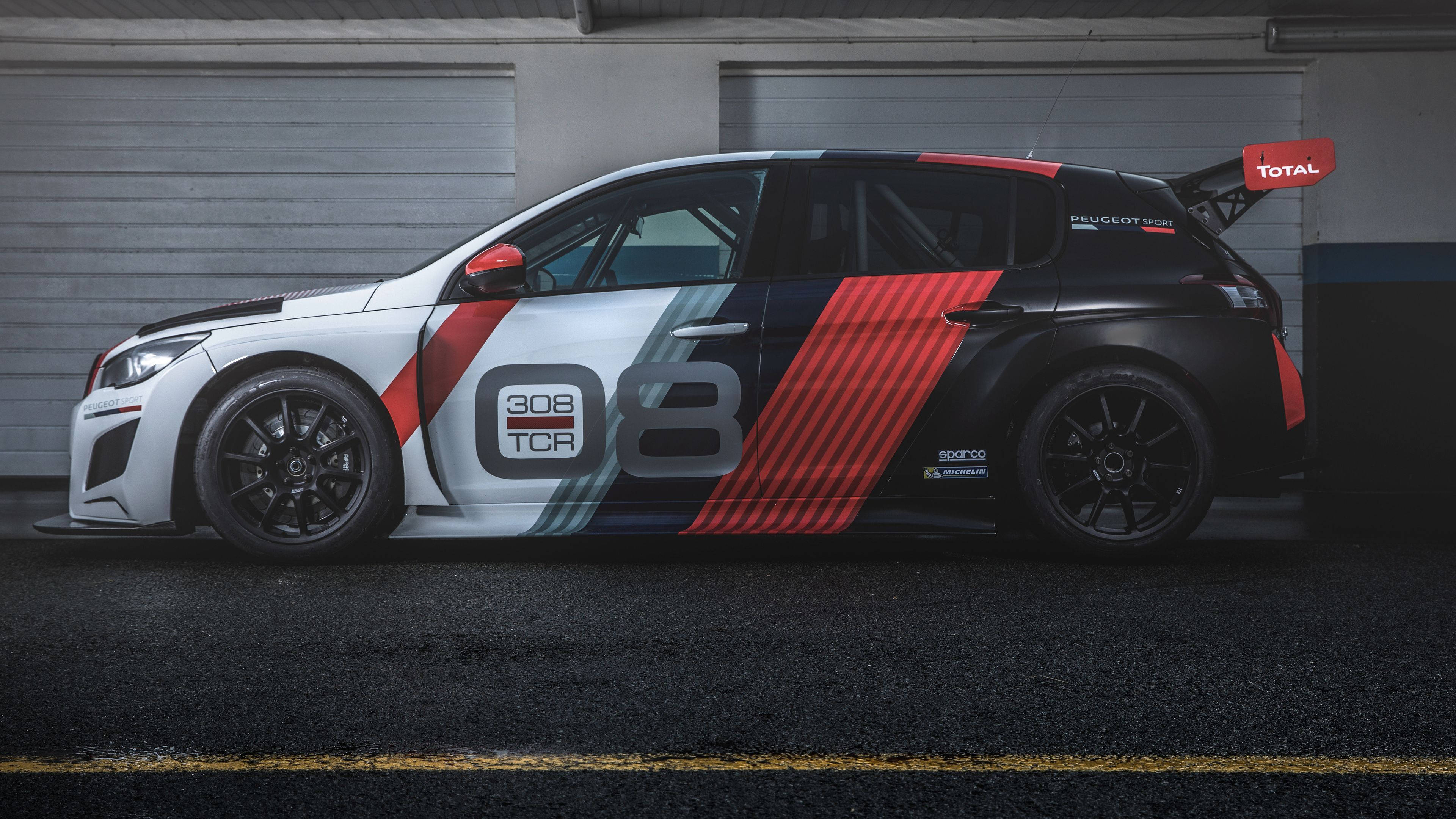 客製化標緻308車型 壁紙 — 一架時尚的Peugeot 308 TCR賽車，帶有醒目的紅、黑、白塗裝，在車庫中蓄勢待發，準備比賽。
