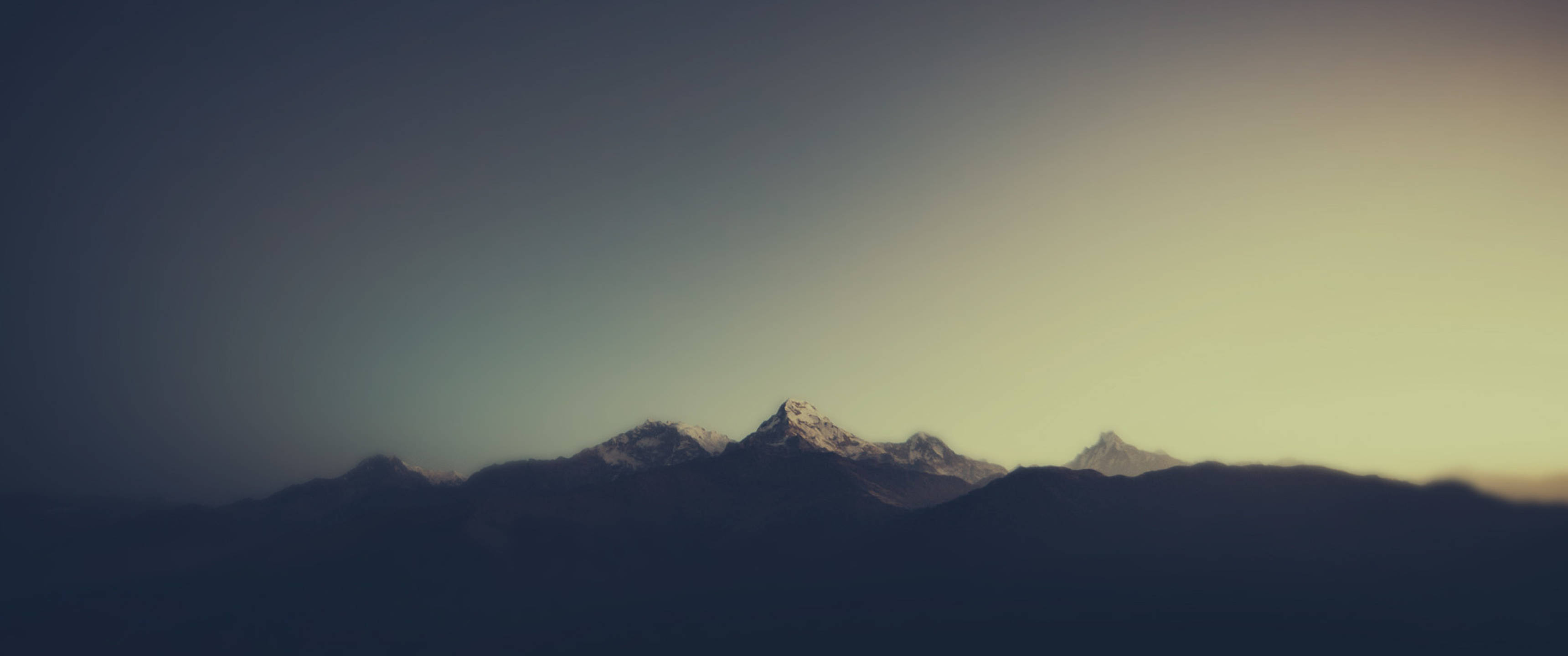 3440x1440 极简主義山巔日出 壁紙 — 積雪的山峰在漸變的天空中升起，散發著夕陽的色調。