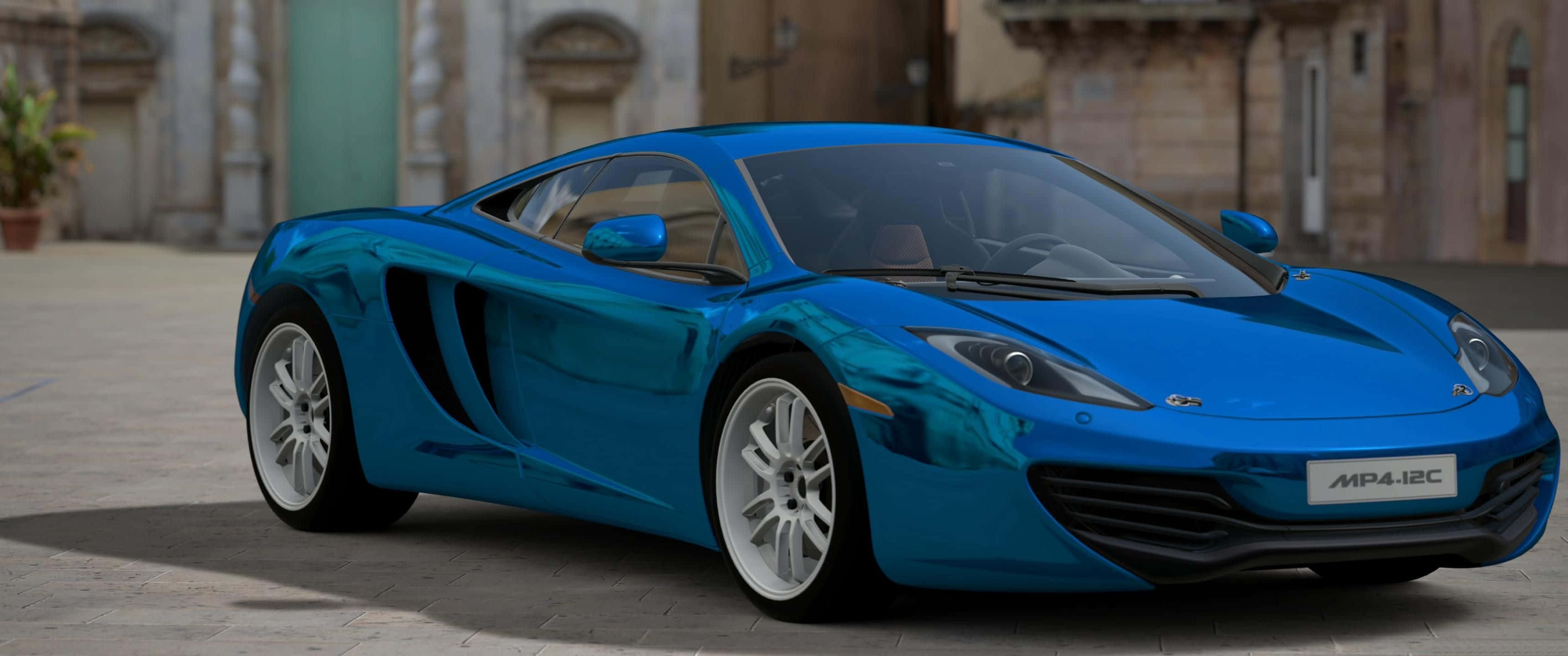 3440x1440 藍色麥拉倫MP4跑車 壁紙 — 一輛光澤的藍色McLaren MP4-12C跑車在日光下閃耀，背景是石鋪廣場和柔焦的歷史建築。