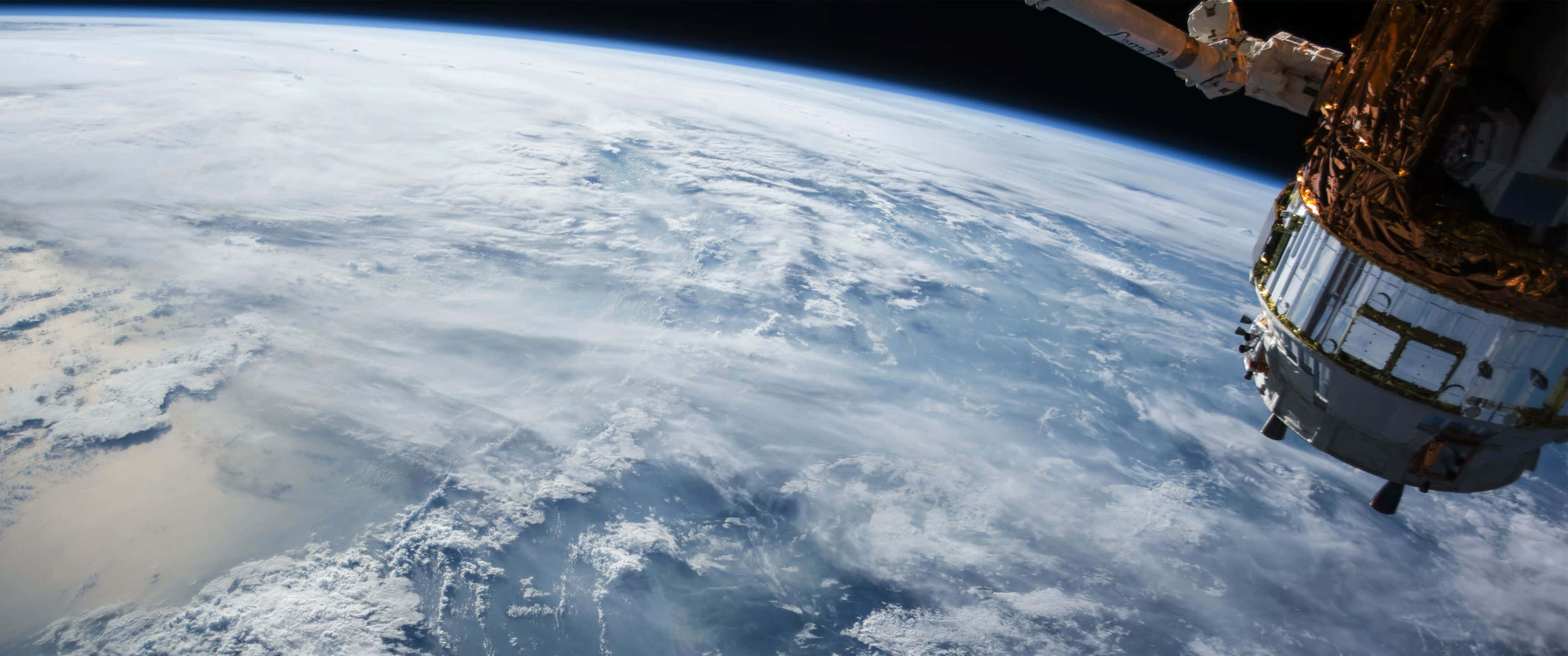 搭乘這款驚豔的超寬 3440x1440 宇宙壁紙，前往無限與更遠方！ 壁紙 — 一艘太空船在地球旋轉的白色和藍色雲層上方盤旋，背景是太空的黑色虛空。