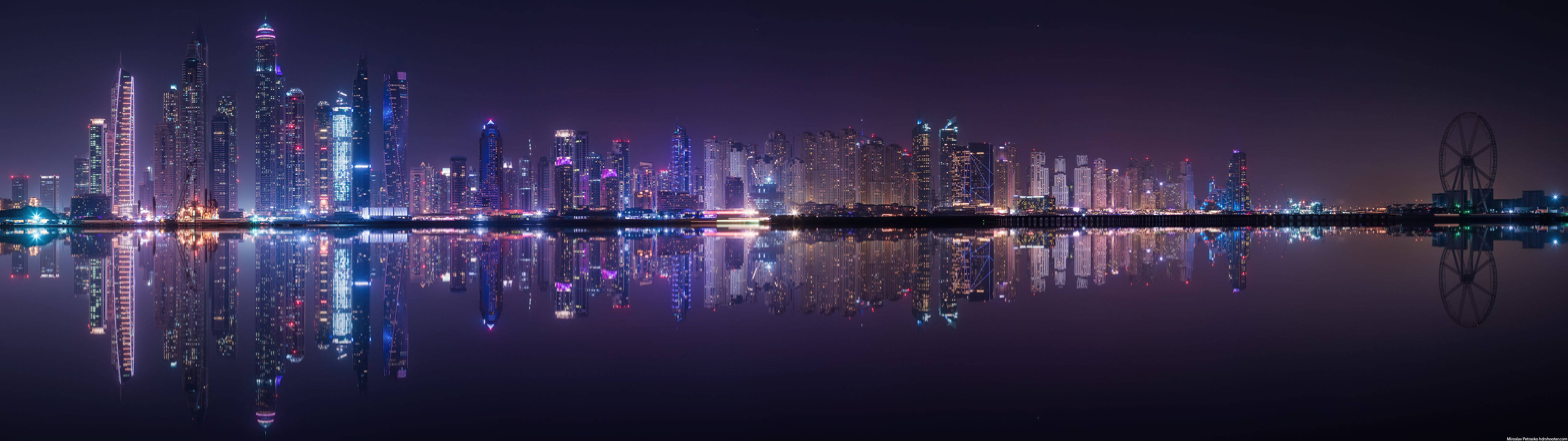 夜晚的杜拜天際線，摩天大樓和摩天輪倒映在水中。