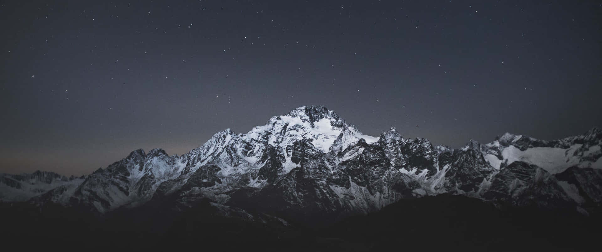 在繁星點點的夜空和微弱極光下的雪山山脈。