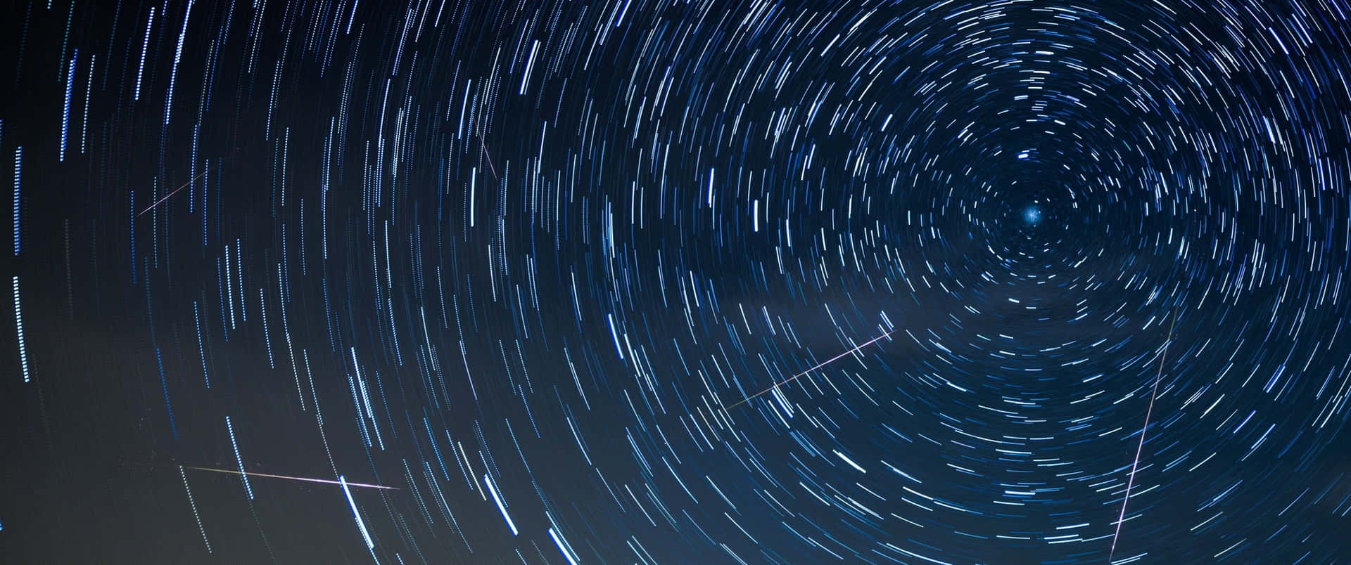 深藍色夜空中以明亮恆星為中心的旋轉星軌。