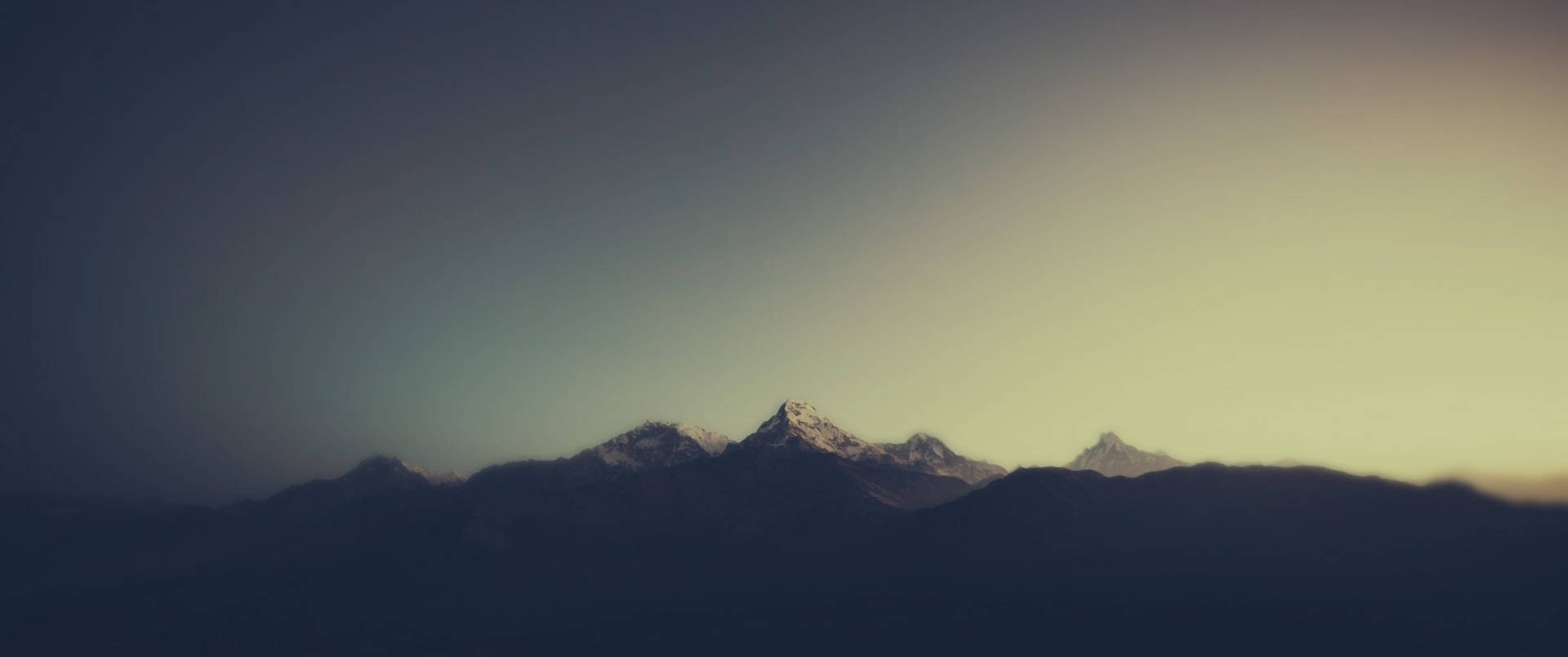 夕陽下漸變天空中的積雪山峰剪影