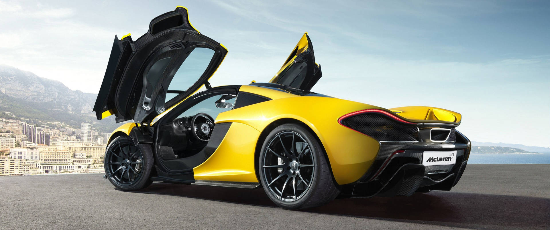 黃色McLaren跑車在沿海公路上打開車門。