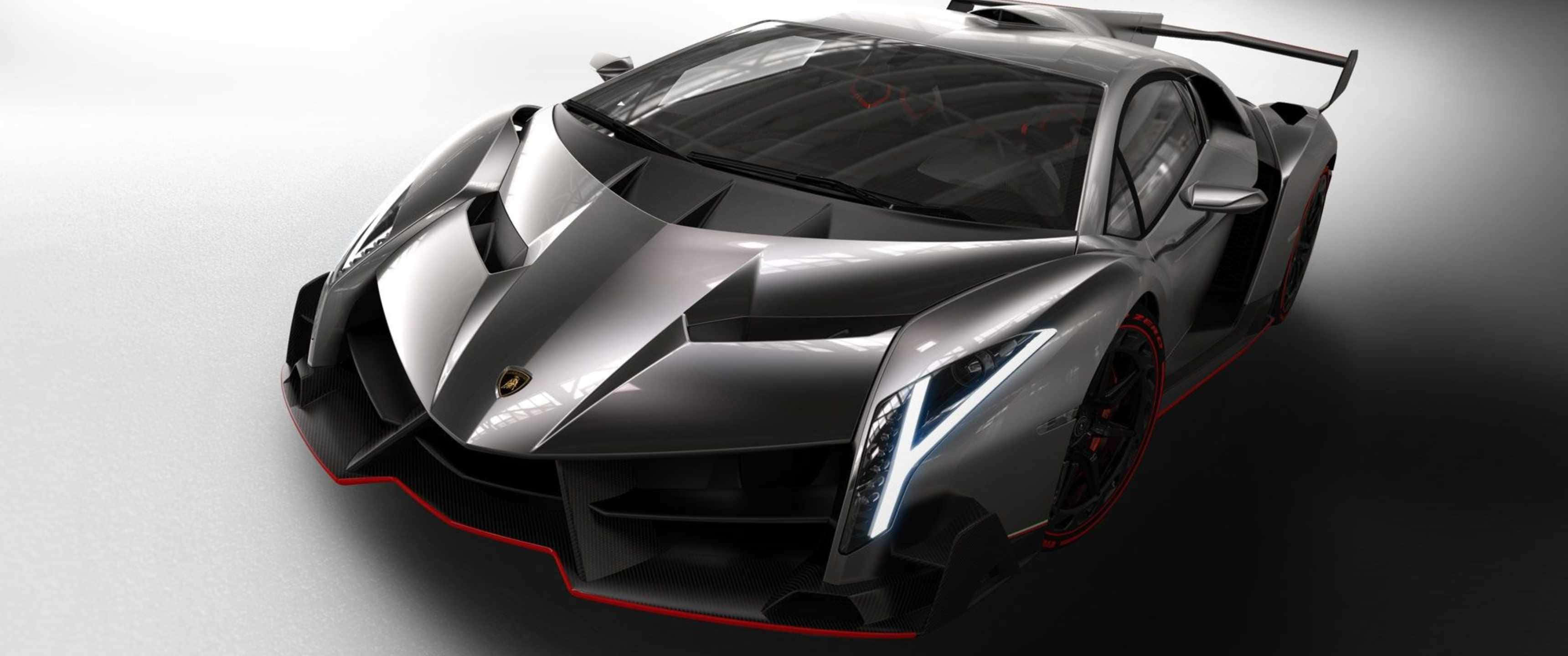 「蘭博基尼的巔峰之作 - 3440x1440p」 壁紙 — 一台時尚的銀色林寶堅尼 Veneno，帶有紅色點綴和發光頭燈，在漸變灰色工作室背景前擺拍。
